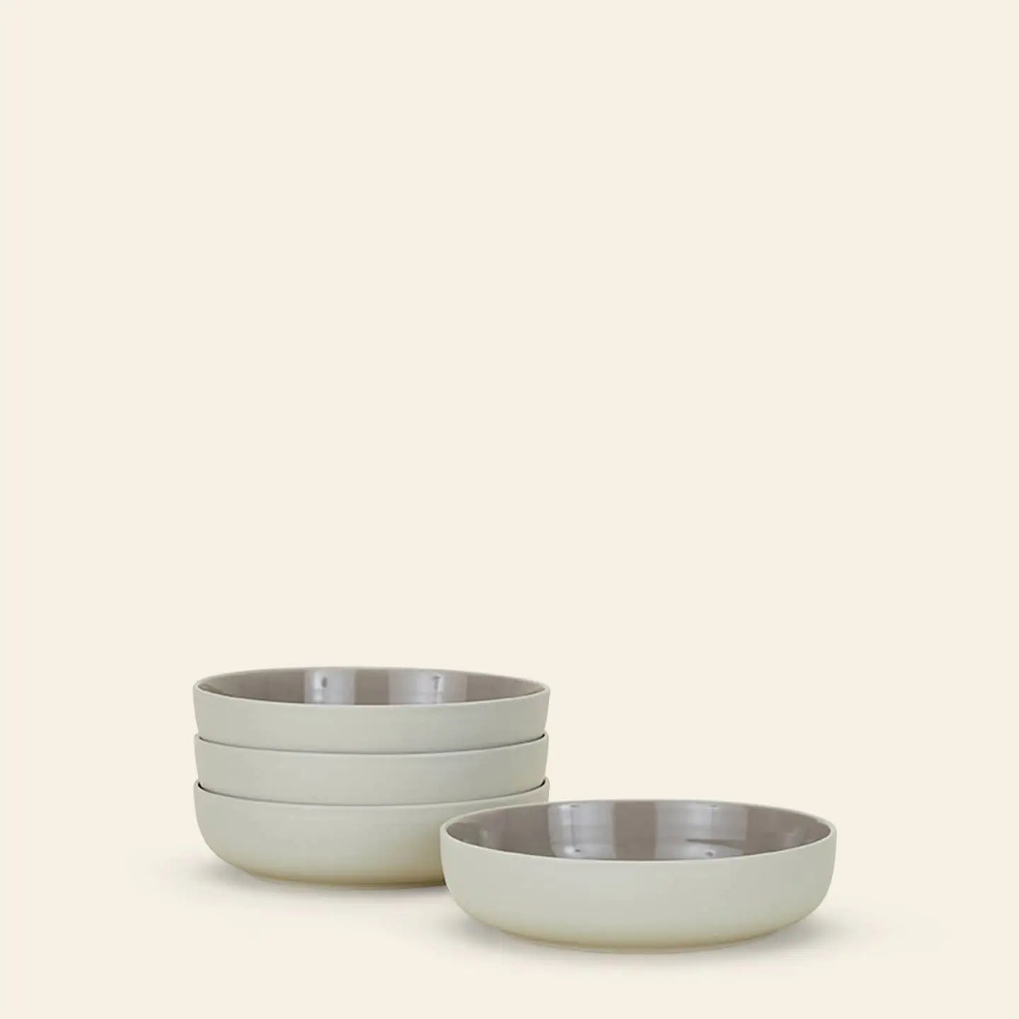A set of four Hawkins New York Essential Low Bowls is stacked on a neutral background, highlighting their simple, modern design and elevating any dining experience.