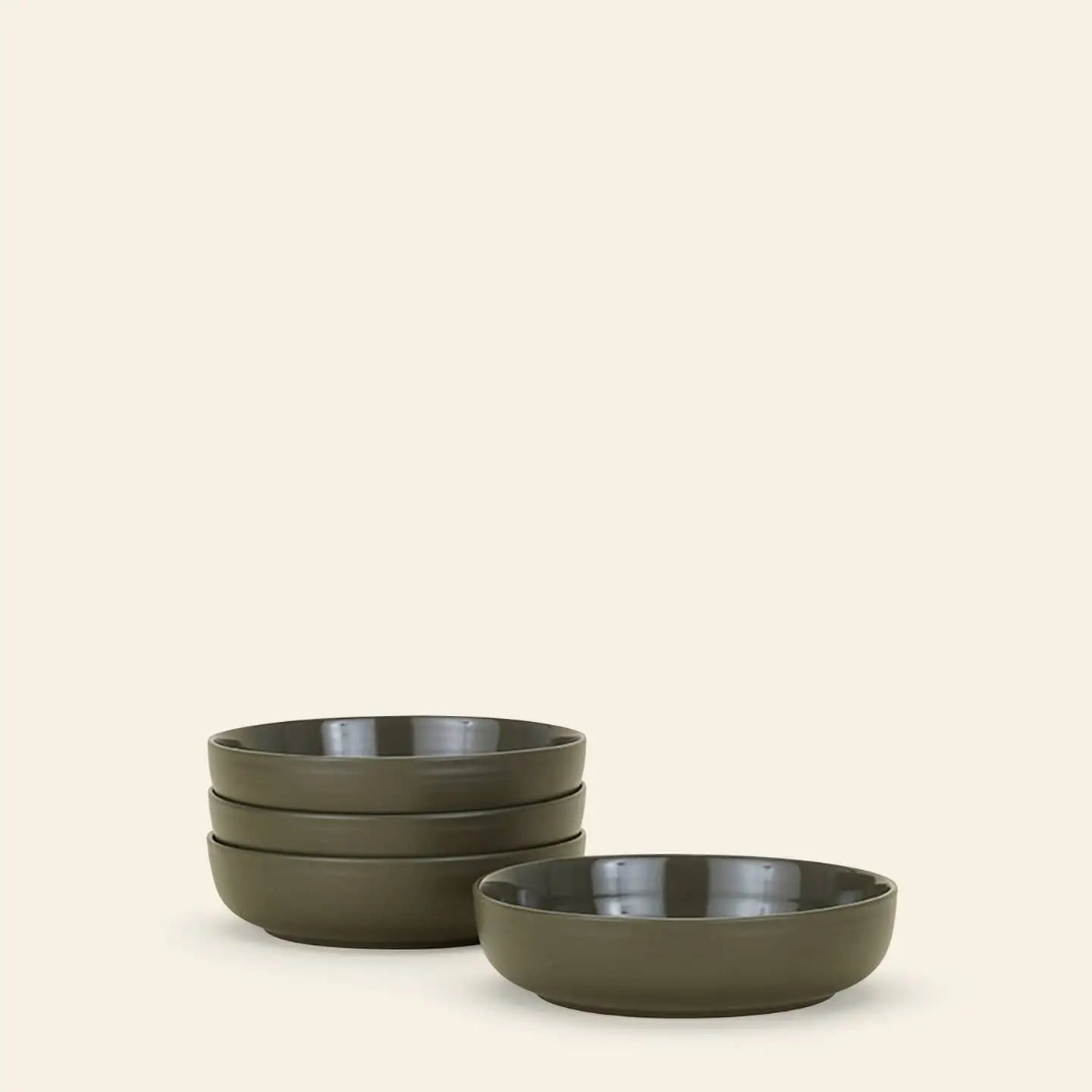 A set of four Hawkins New York Essential Low Bowls is stacked on the left, with another matching bowl in front and to the right, all against a plain beige background—ideal for elevating any dining setting.
