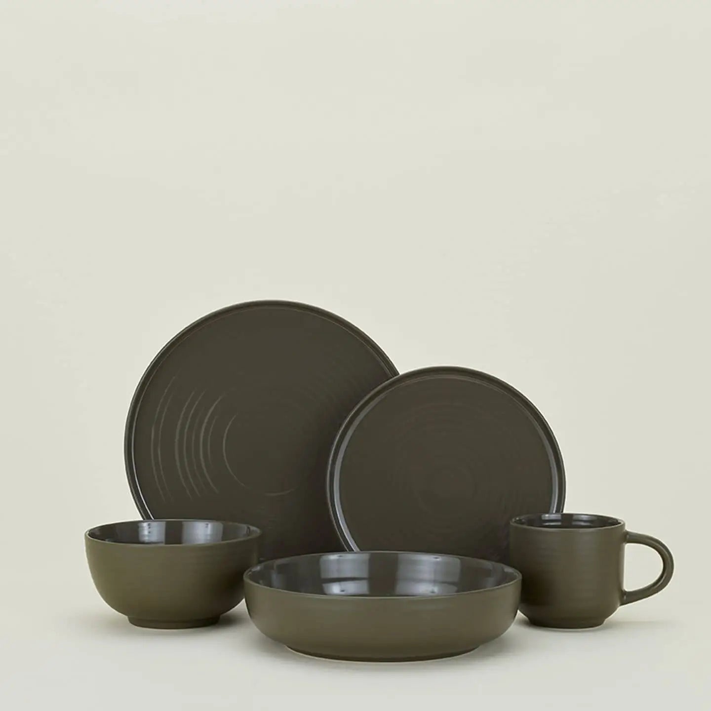 A set of four matte dark gray Hawkins New York Essential Low Bowls, stylishly arranged against a light beige background to elevate your dining experience.