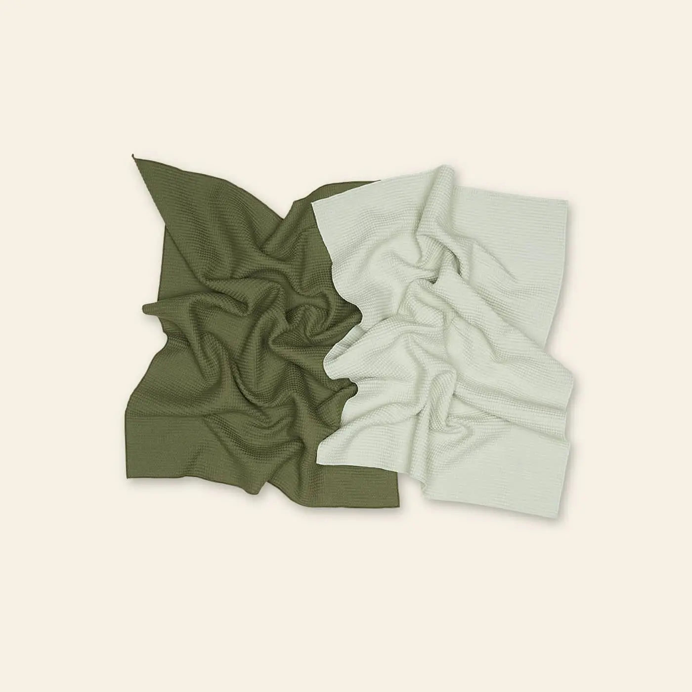 Two Hawkins New York Essential Waffle Dish Towels, one in olive green and one in light gray, are placed side by side on a neutral beige background.