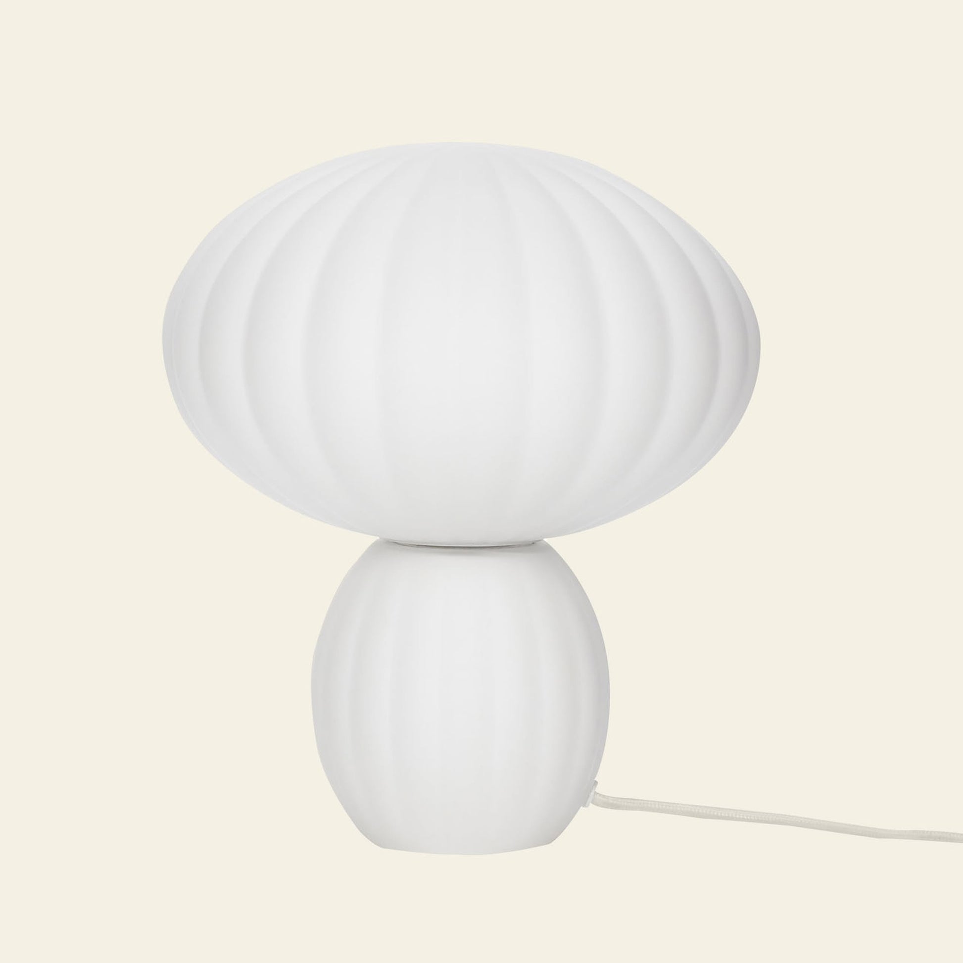 The Hübsch Kumu Table Lamp by Hübsch features a white, ribbed, rounded top and an oval frosted glass base for a modern minimalistic look. A white electrical cord extends from the base against a plain light background.