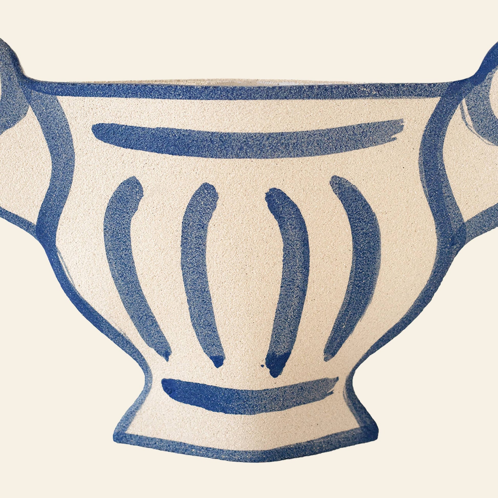 The INI CERAMIQUE Greek Coupe Ceramic Vase by INI CERAMIQUE is an off-white handcrafted piece with a textured surface, abstract blue lines, bold patterns, and dual side handles evoking ancient Greek pottery.