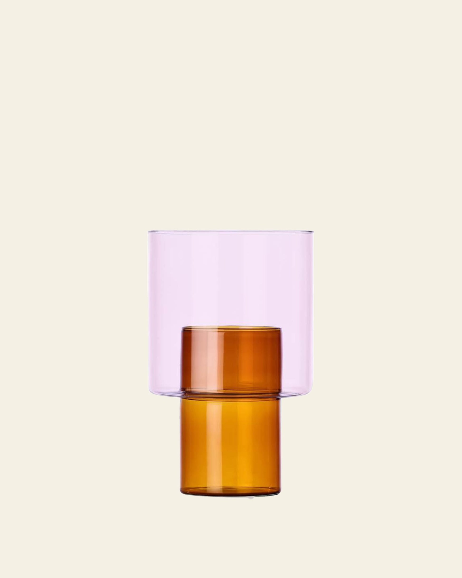 The Ichendorf Milano Boreale Vase B by Ichendorf Milano is a modern borosilicate glass vase with a double-cylinder design, featuring a transparent light purple top and amber-brown bottom, displayed on a plain beige background.