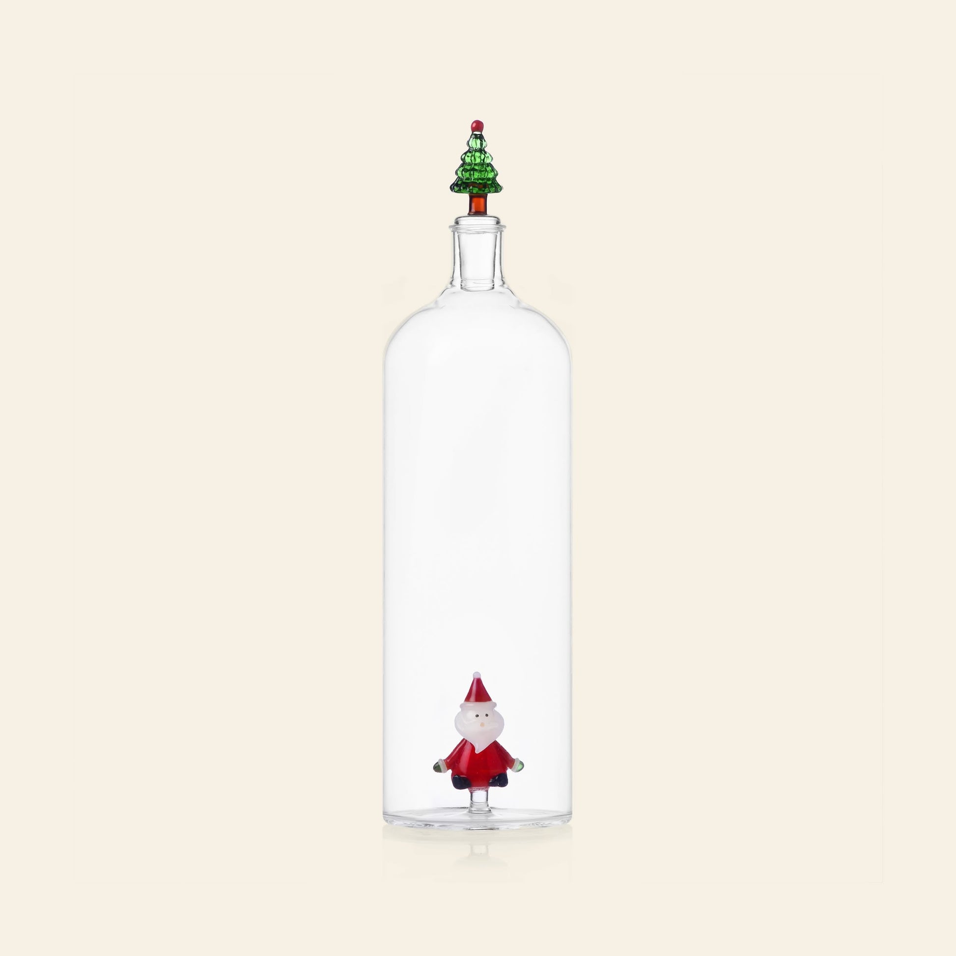 The Ichendorf Milano Christmas Tales Bottle by Ichendorf Milano features clear glass, a small Santa figurine inside, and a decorative tree-shaped stopper, set against a simple light background.