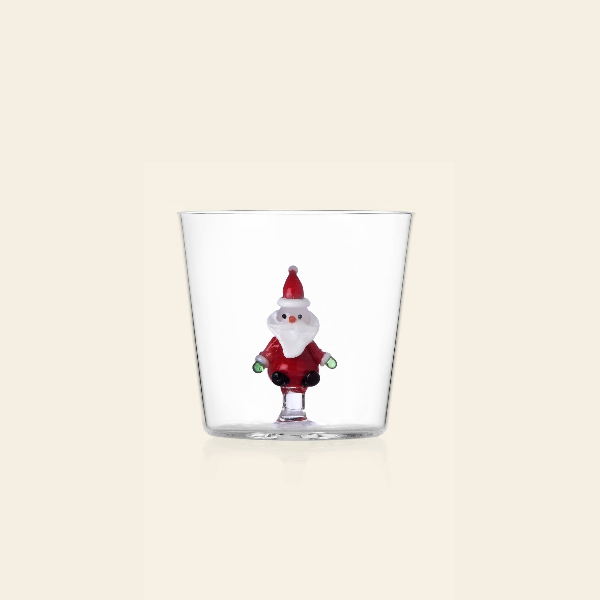 The Ichendorf Milano Christmas Tales Tumbler by Ichendorf Milano features a clear glass design with a colorful Santa figurine at the base, making it a delightful holiday gift or festive addition to any glassware collection.