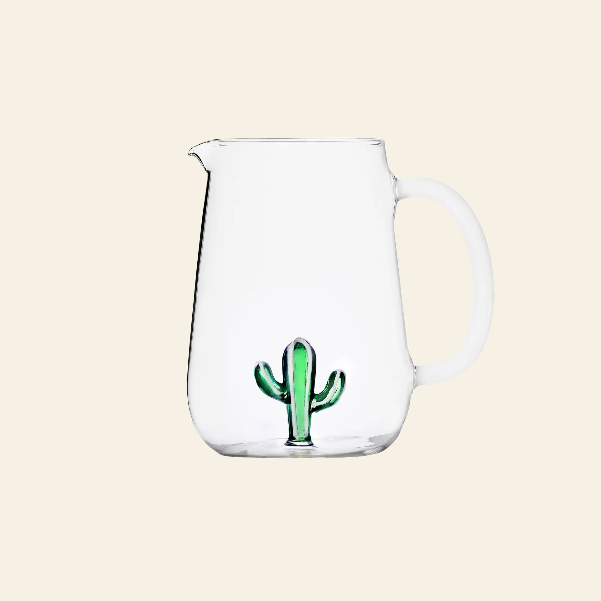 The Ichendorf Milano Desert Plants Pitcher is a clear glass pitcher with a handle and a small green cactus motif at the bottom, showcasing handcrafted glassware by Ichendorf Milano against a plain beige background.