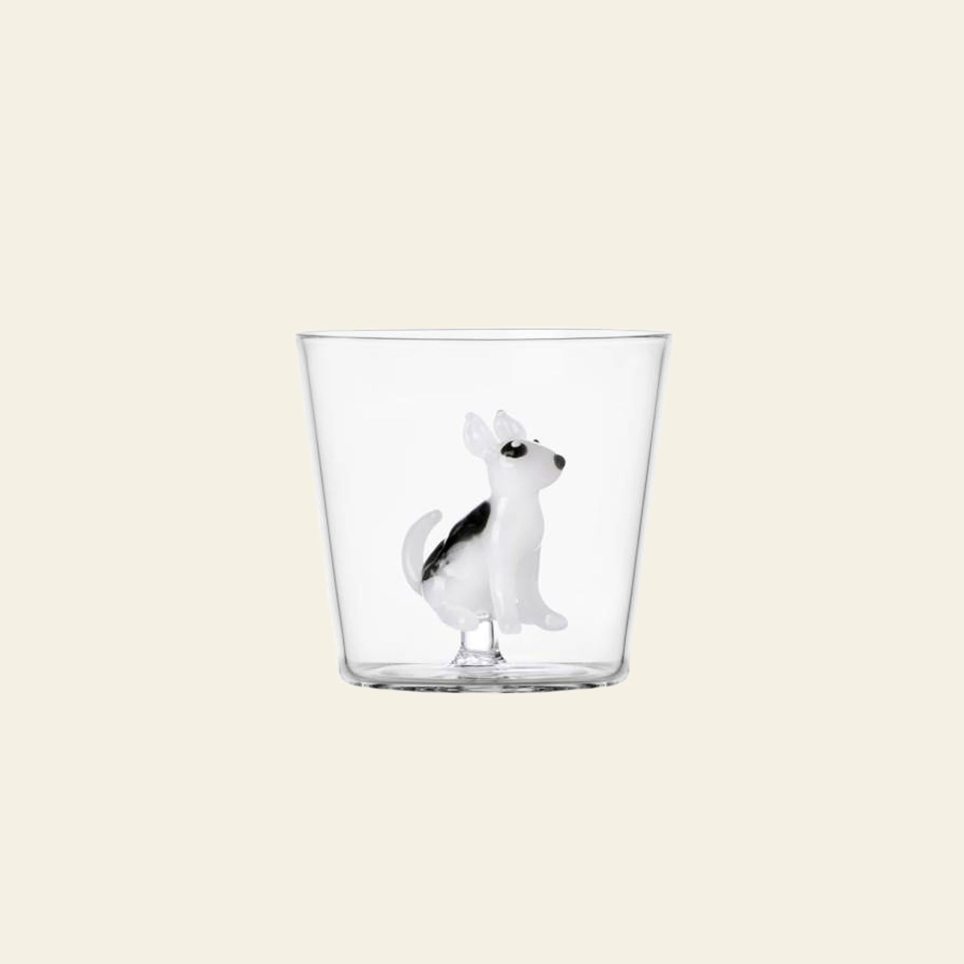 The Ichendorf Milano Dogs Tumbler - Bull Terrier is a clear glass by Ichendorf Milano, featuring a small black and white Bull Terrier figurine inside, set against a plain light beige background.