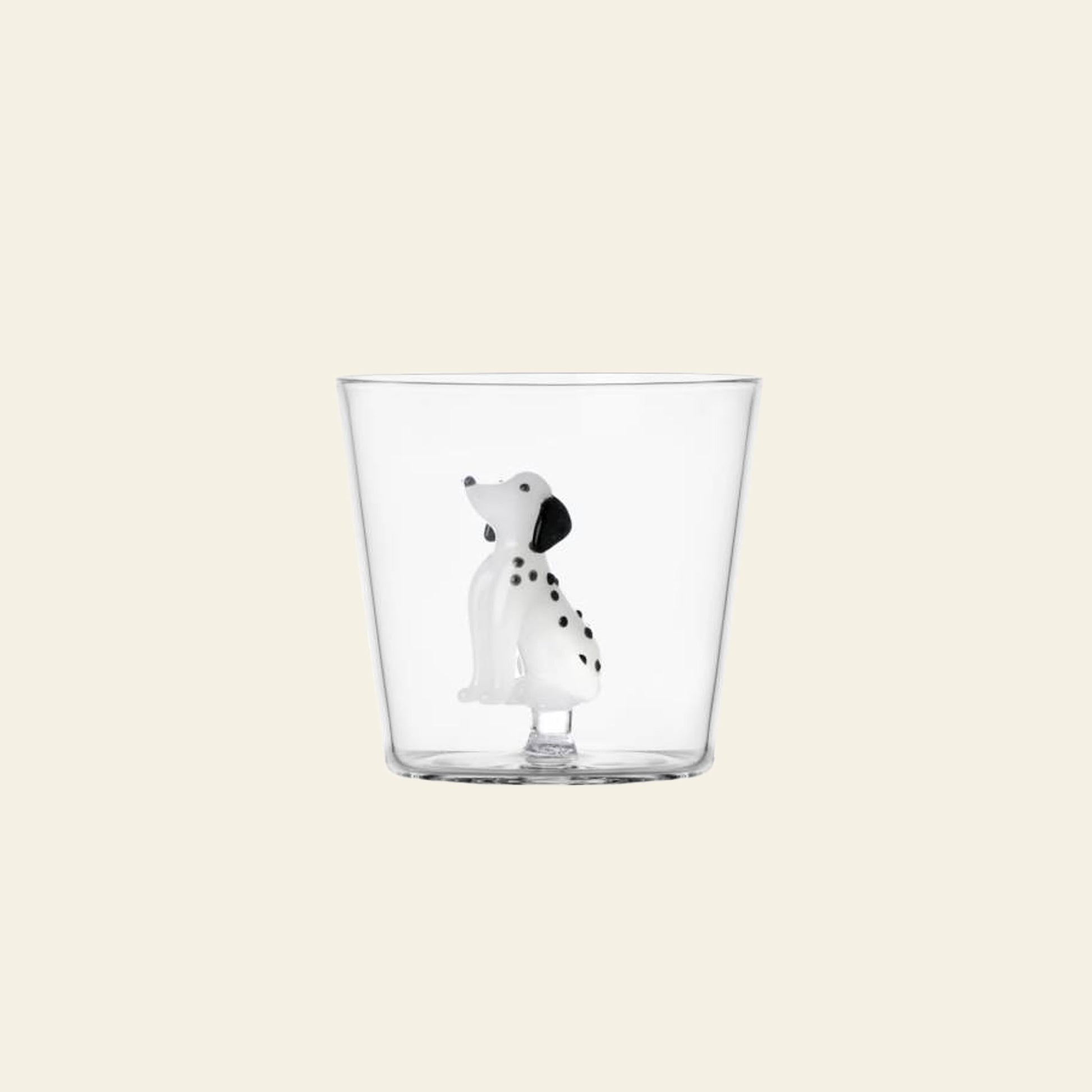 The Ichendorf Milano Dogs Tumbler - Dalmatian by Ichendorf Milano is a clear artisan glass with a delicate white-and-black Dalmatian figurine inside, presented against a simple light background.