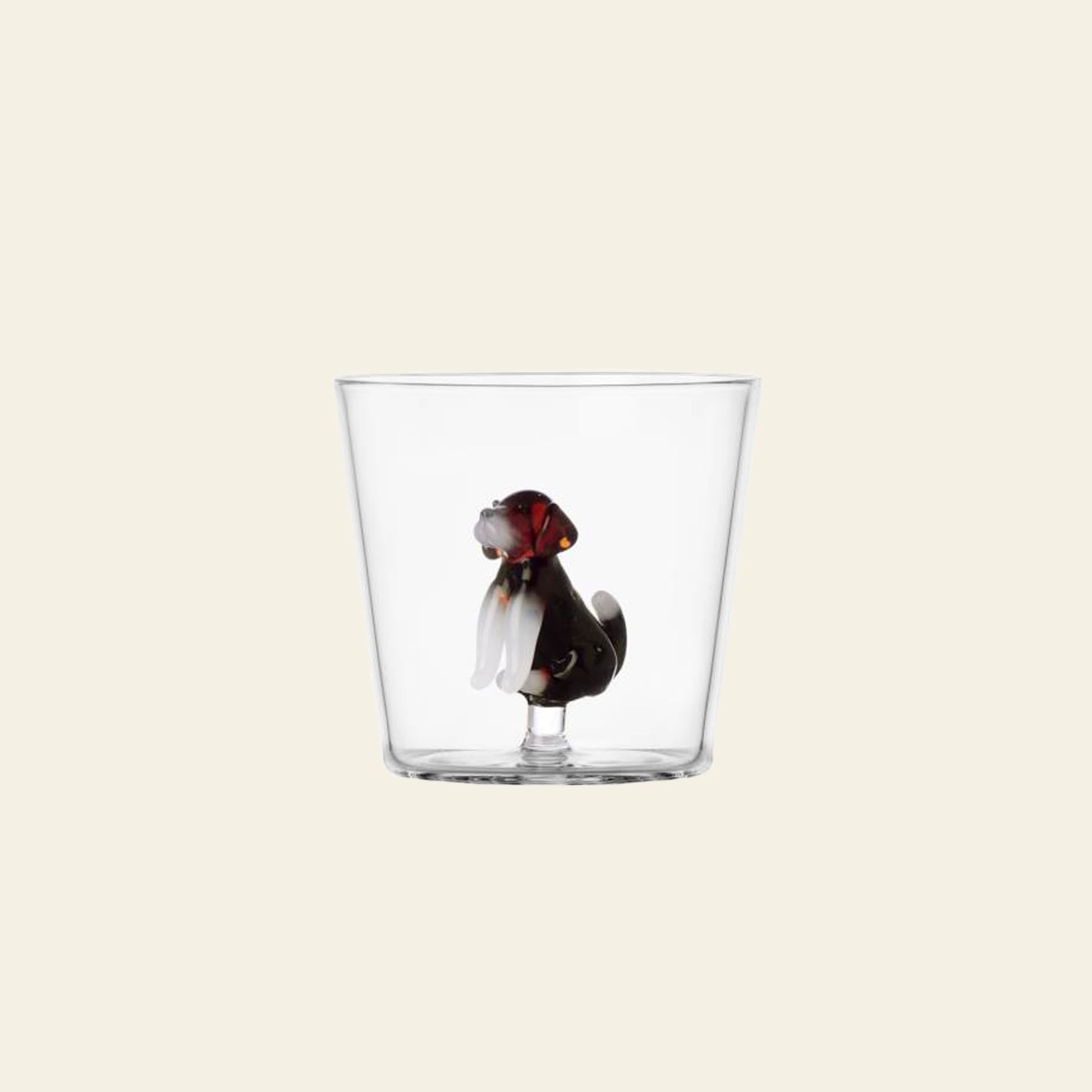 The Ichendorf Milano Dogs Tumbler - English Foxhound is a clear handmade glass featuring a sculpted English Foxhound with droopy ears and a red collar inside, making it a charming display piece from Ichendorf Milano.