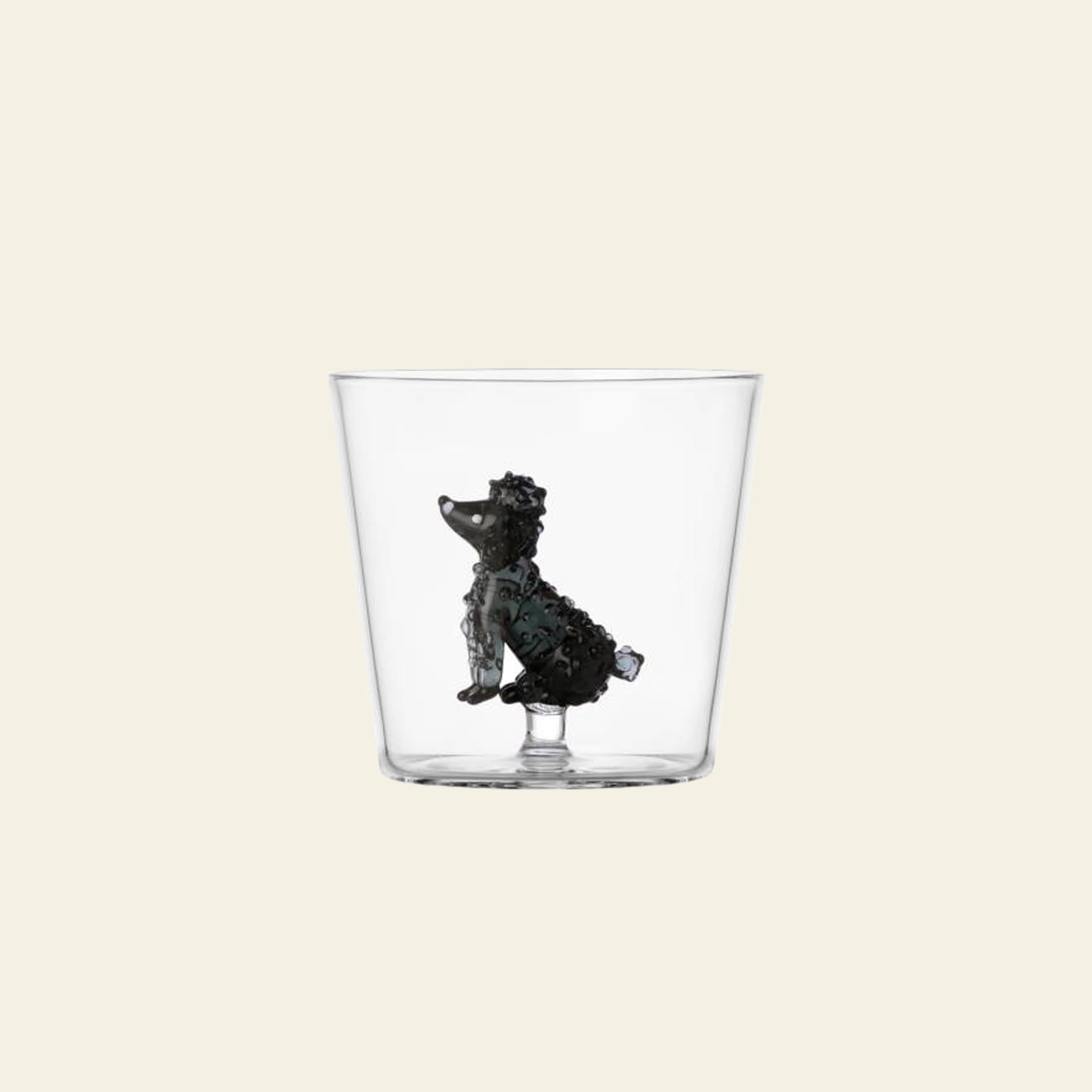 The Ichendorf Milano Dogs Tumbler - Poodle by Ichendorf Milano is a clear glass with a small, detailed black poodle figurine attached inside the base, set against a simple light background.