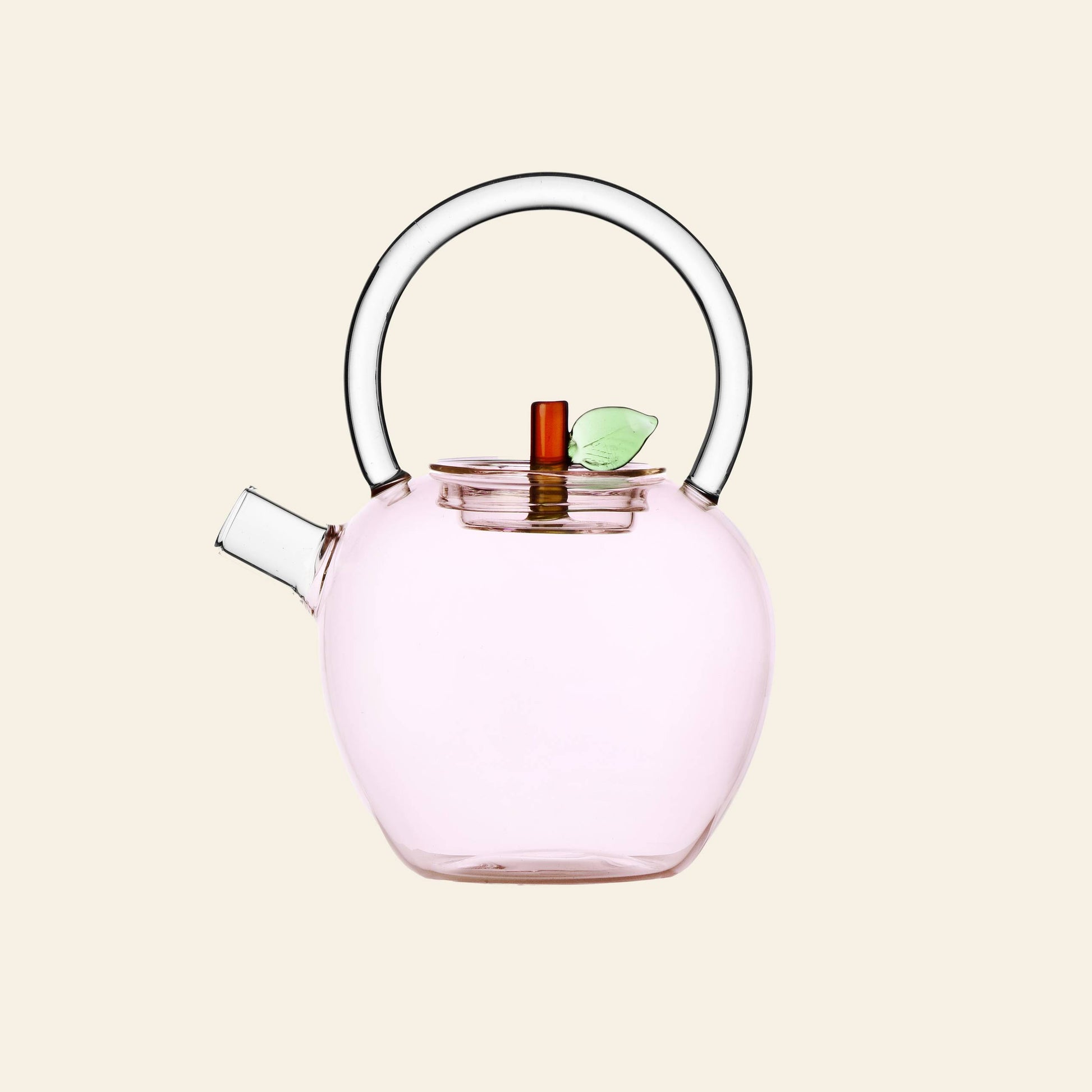 The Ichendorf Milano Fruits and Flowers Teapot by Ichendorf Milano features a transparent, round, light pink body with a clear handle, small spout, and a lid adorned with a brown stem and green leaf. Inspired by Alessandra Baldereschi’s collection.