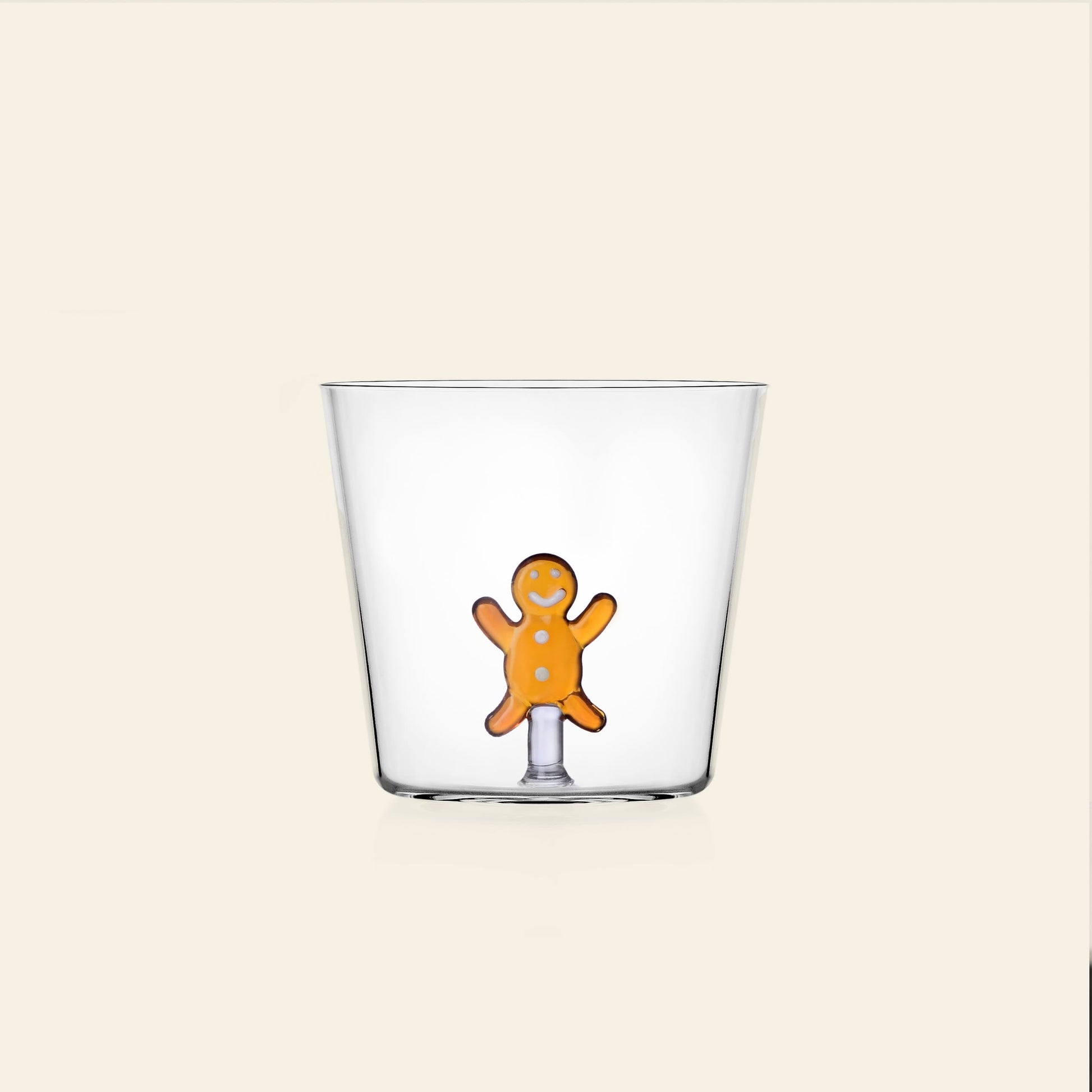 The Ichendorf Milano Sweet and Candy Tumbler by Ichendorf Milano features a clear design with a small orange gingerbread man at the base, set against a plain light beige background—ideal for the holiday season.