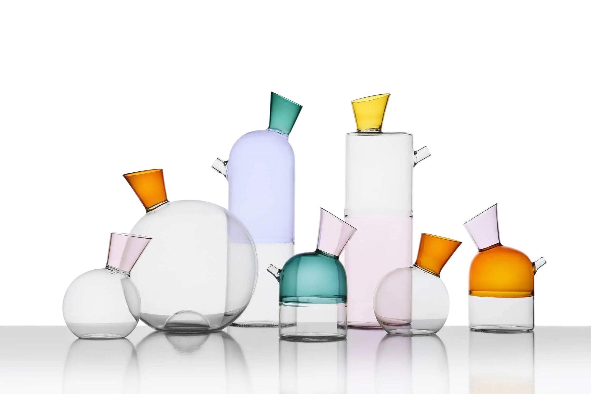 The Ichendorf Milano Travasi Oil Bottle by Ichendorf Milano features a modern geometric design with glass vessels in various shapes and vibrant pastel tops—ideal for adding style to any table setting.