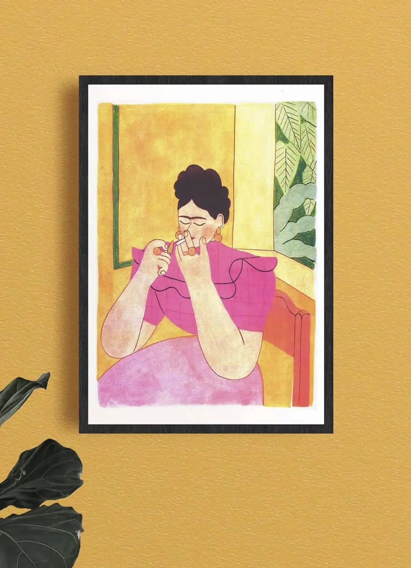 The KIBLIND Atelier Morgane Fadanelli - Frida Kahlo print by KIBLIND Atelier features a figure in a pink dress with short dark hair holding a small object, set against a mustard yellow background with green leaves—ideal for risography printing.