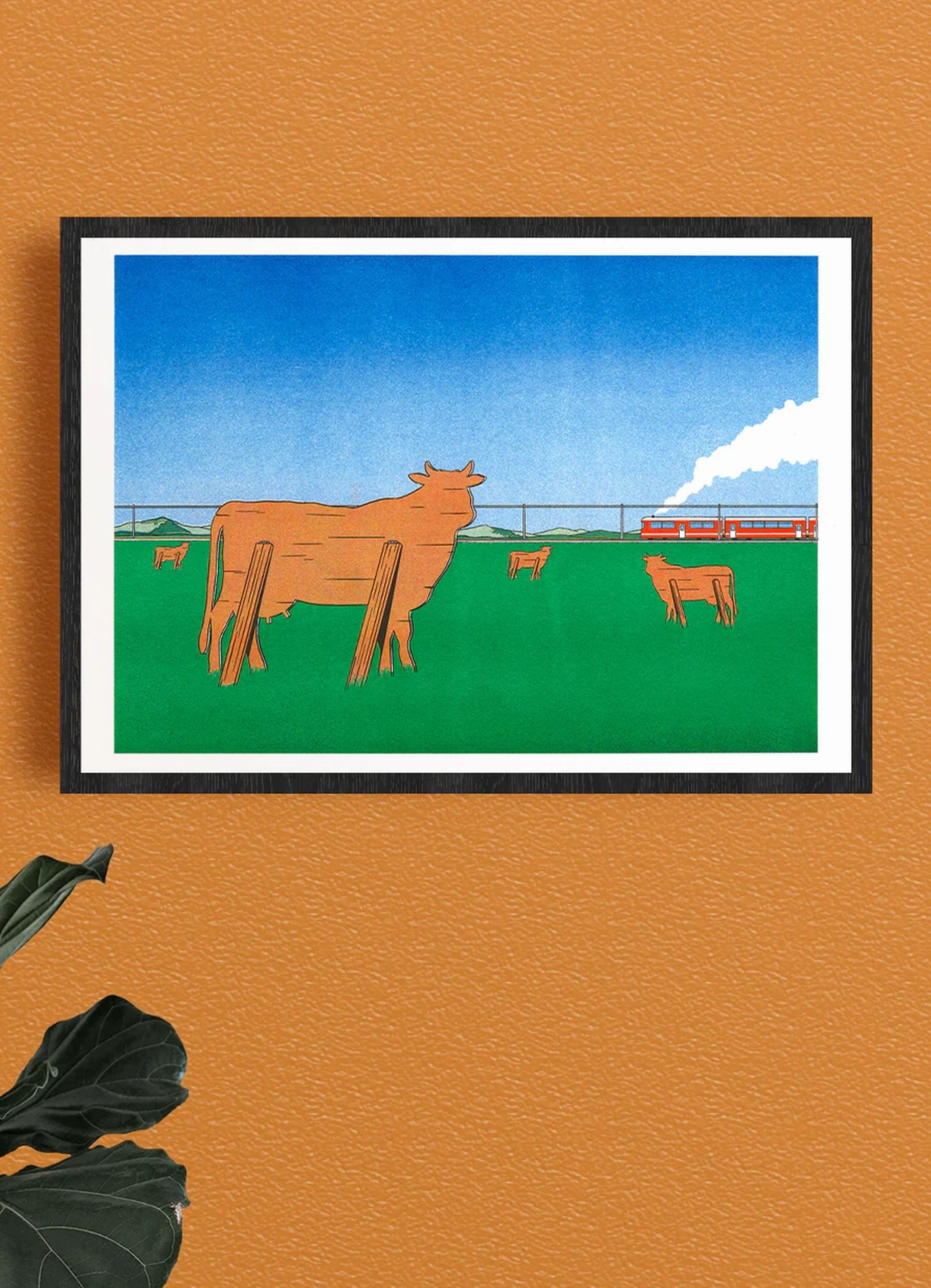 KIBLIND Atelier’s Watching the Trains Go By by Simon Bailly features abstract wooden cows in a green field, a red train with white smoke, and evokes Franco-Belgian comic art, set on an orange wall with a plant leaf in the corner.
