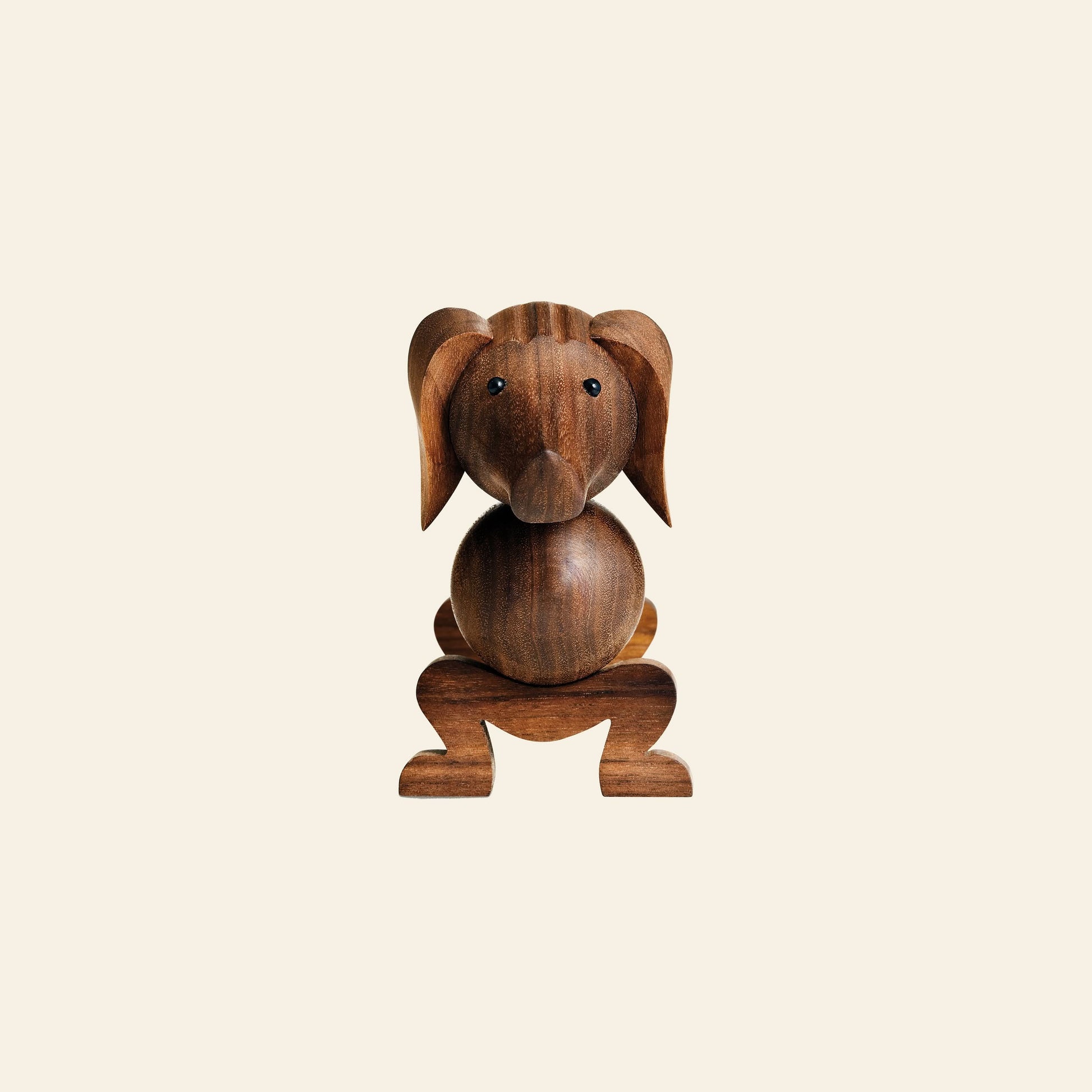 A playful Kay Bojesen Dog Small wooden figurine by Kay Bojesen, featuring a round body, large ears, and curved legs—an iconic animal companion—set against a light beige background.