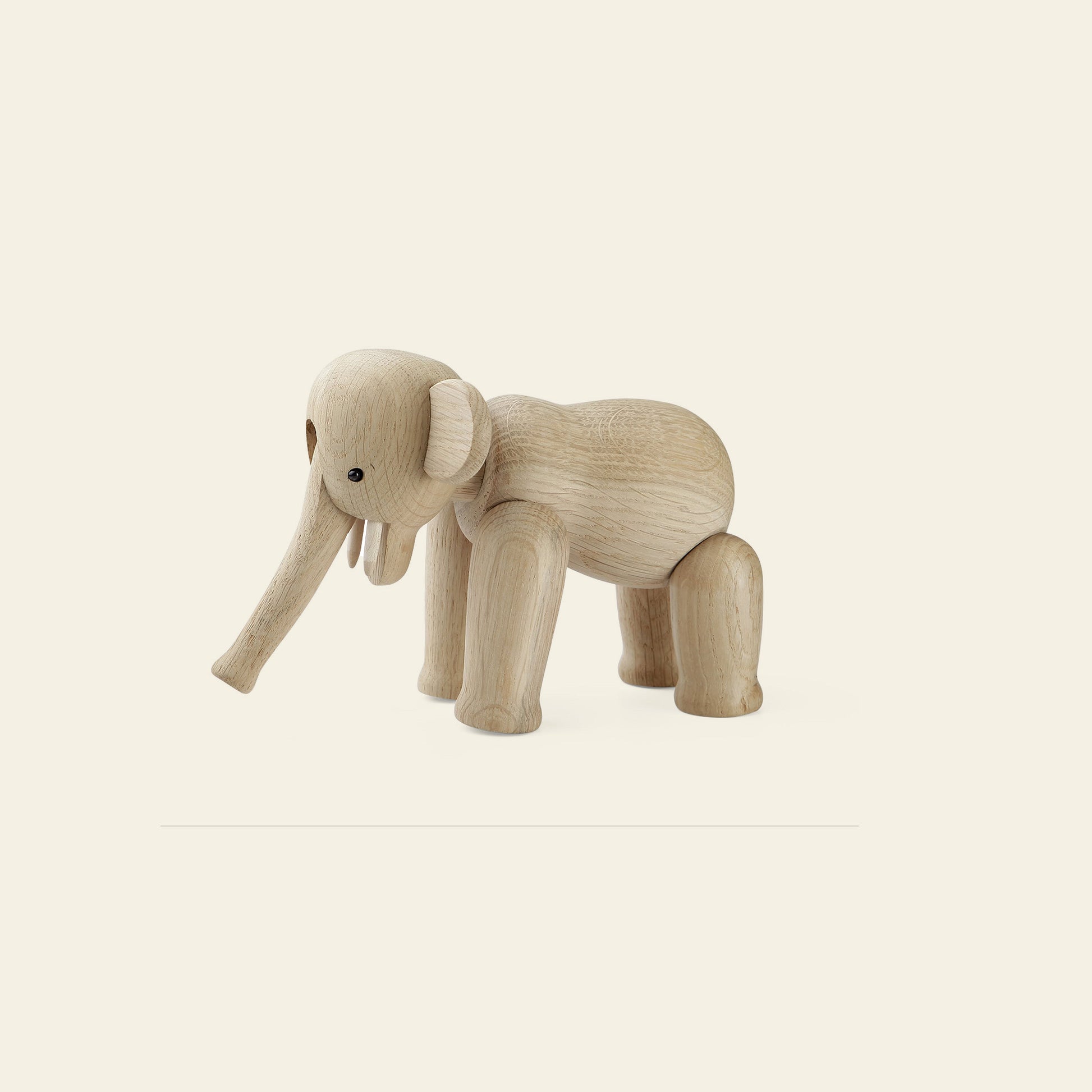The Kay Bojesen Elephant Mini by Kay Bojesen, featuring moveable legs and a curved trunk in classic Danish design, stands on a plain, light background.