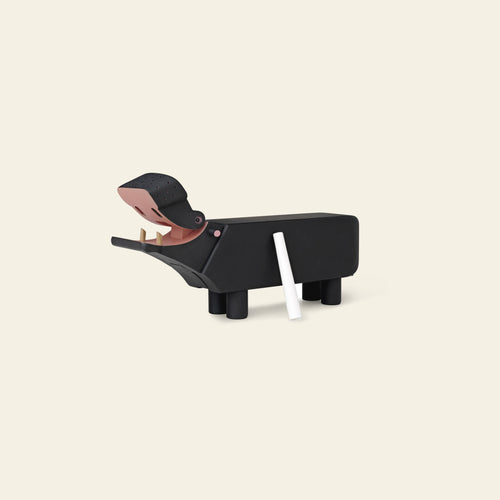 The Kay Bojesen Hippo by Kay Bojesen is shaped like a black hippopotamus with blackboard paint, standing on four legs with an open mouth and white chalk at its side, displayed against a beige background.