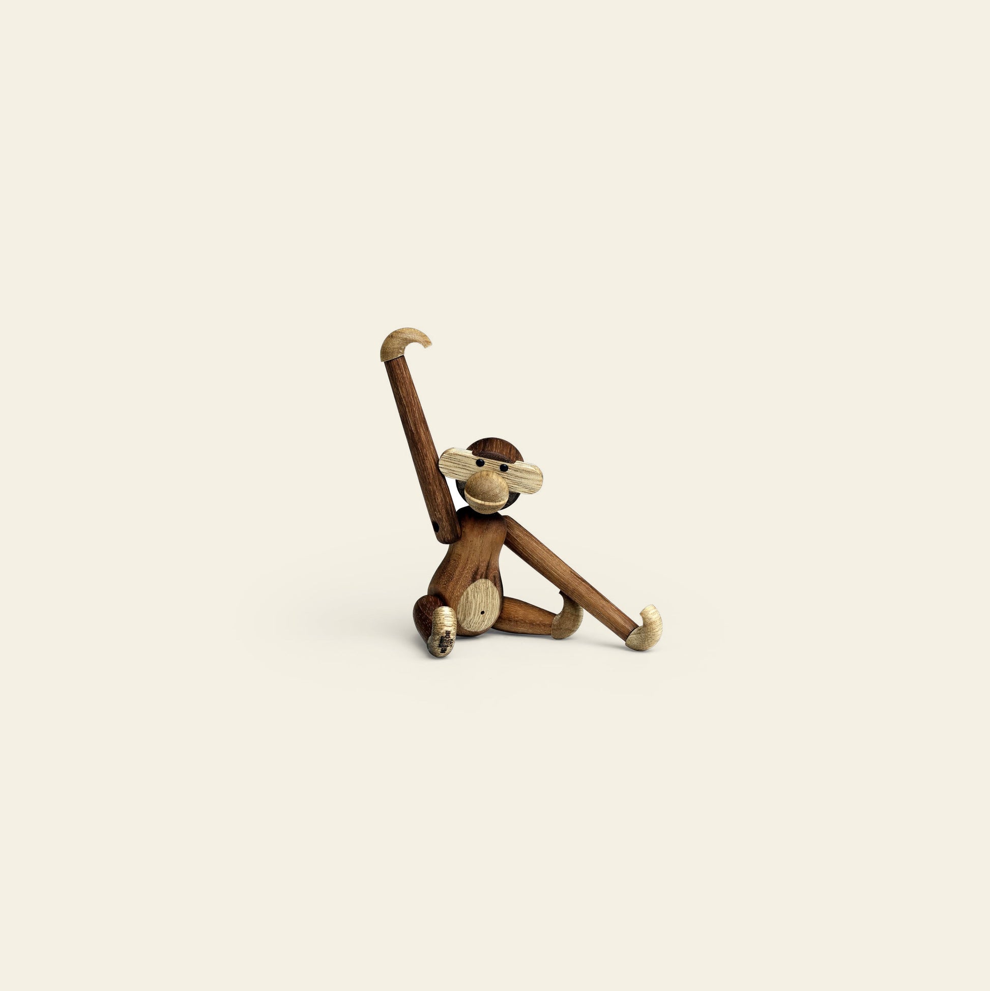 A collectible keepsake, the Kay Bojesen Monkey Mini by Kay Bojesen features articulated limbs and strikes a playful pose—one arm raised high, the other resting on a cream background.