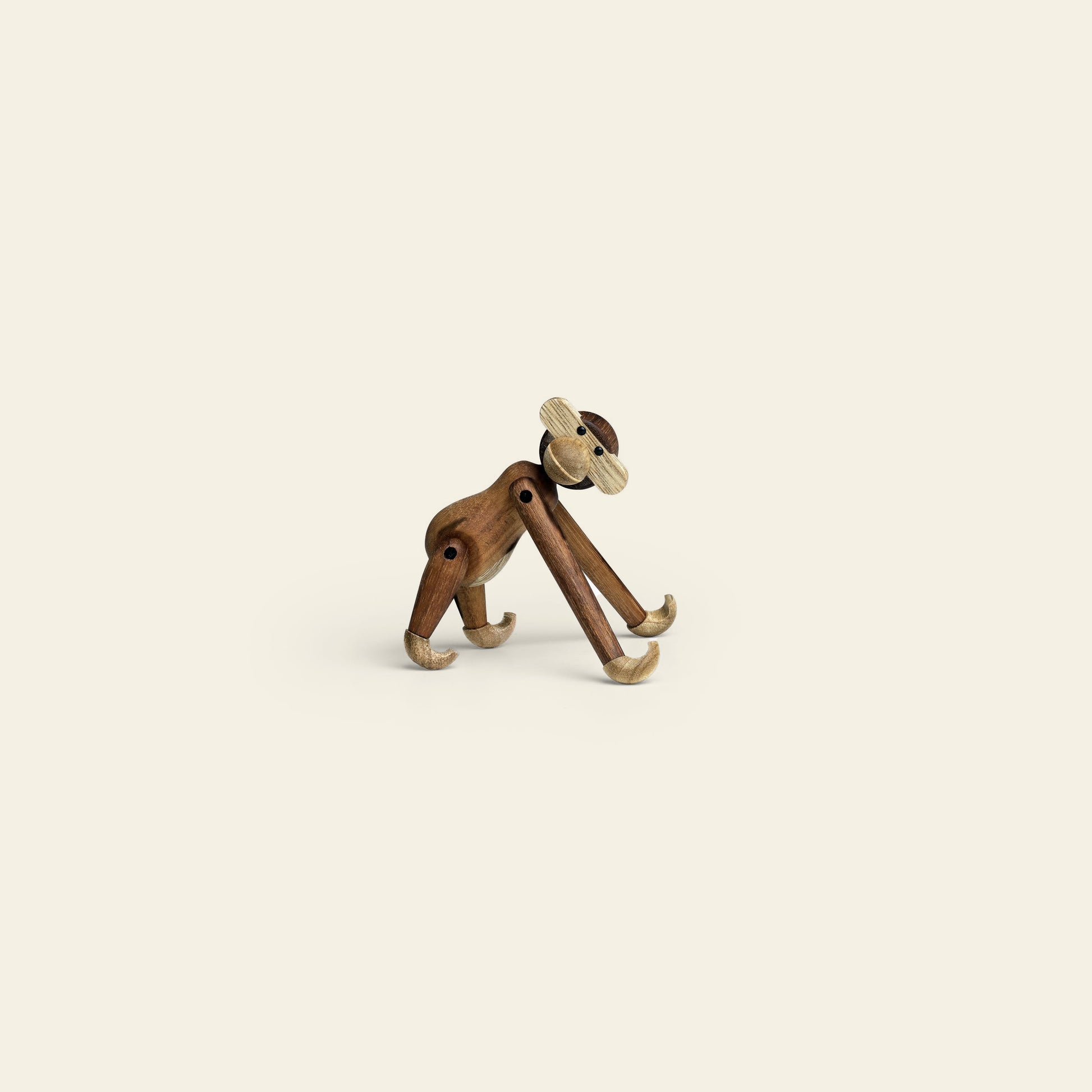 The Kay Bojesen Monkey Mini by Kay Bojesen, crafted from dark and light wood with movable limbs, stands on all fours against a plain beige background—an iconic collectible for any admirer.