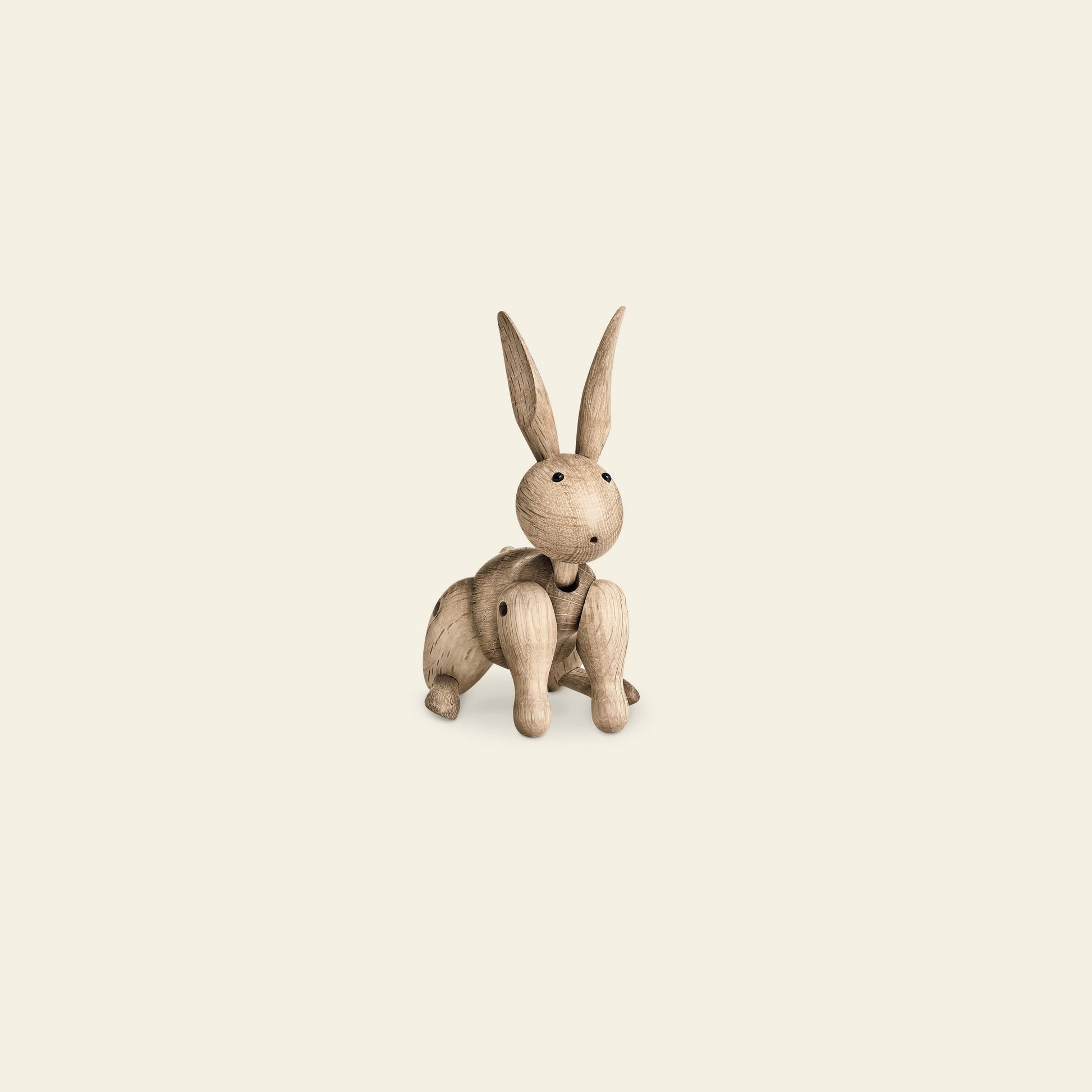 The Kay Bojesen Rabbit Mini by Kay Bojesen is a small, whimsical wooden figurine with movable limbs, sitting upright on a cream background—an example of classic Danish craftsmanship.