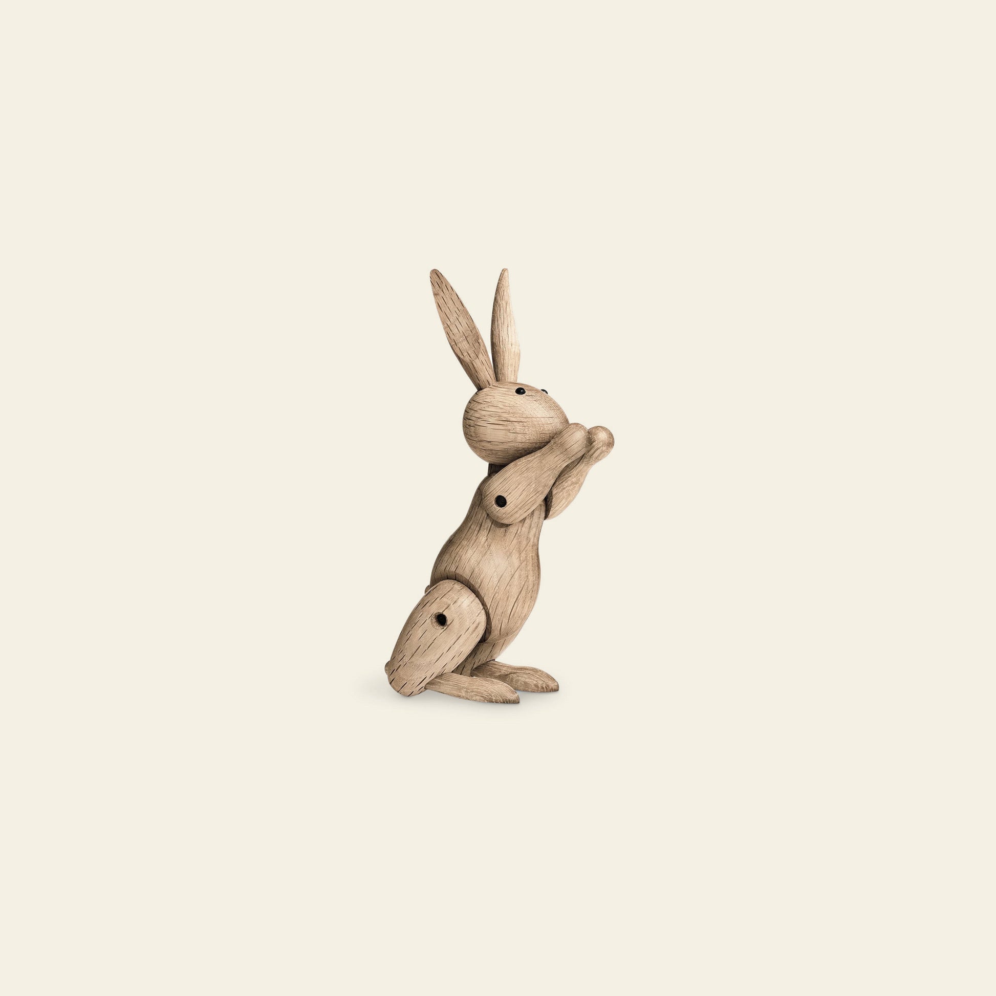 The Kay Bojesen Rabbit Mini by Kay Bojesen is a wooden figurine with movable joints, sitting upright with front paws together—a charming example of Danish craftsmanship—set against a simple light background.