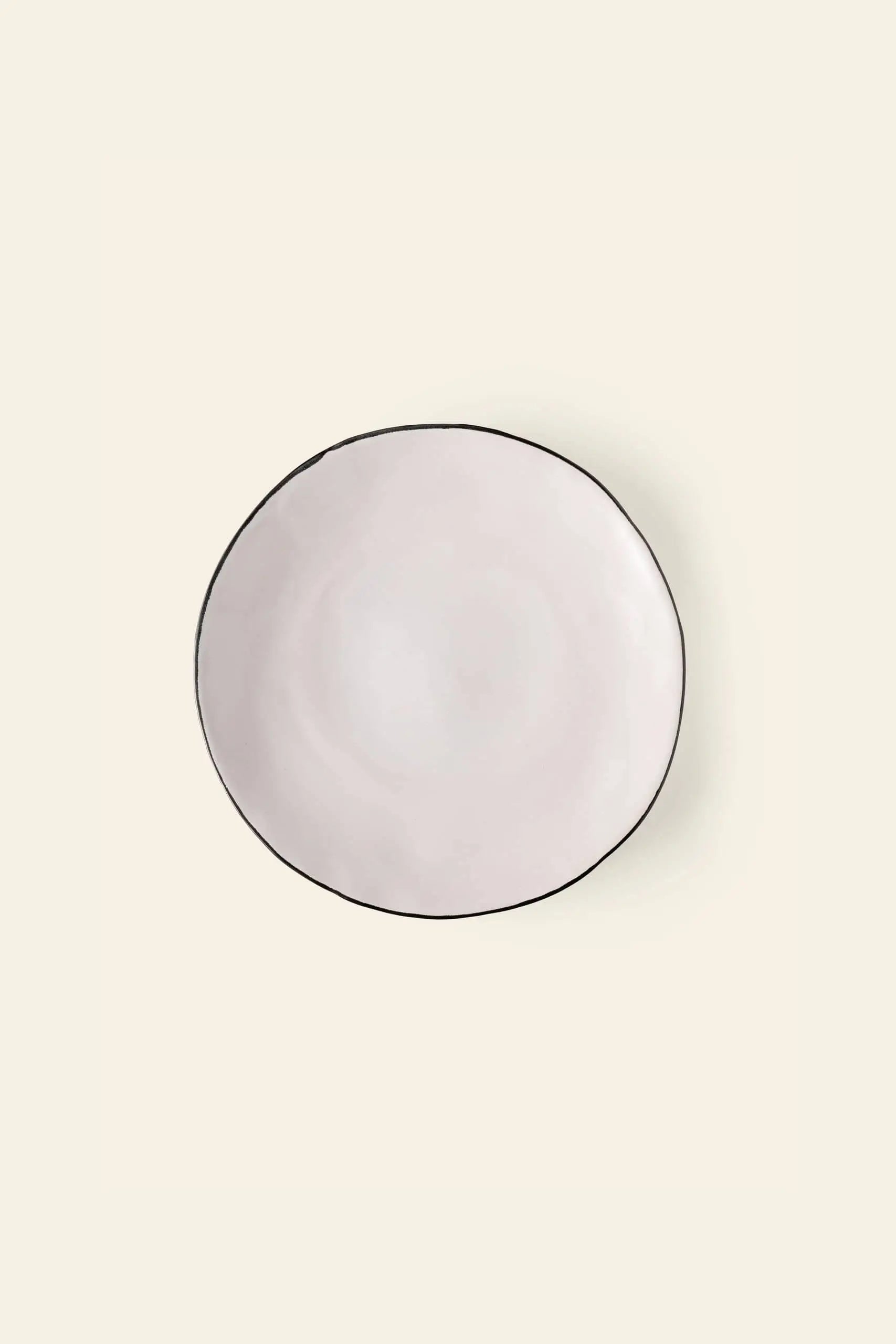 The Kra Sanctuary Andaman Free-Form Dinner Plate features a classic white ceramic glaze, a handmade organic shape, and a slim dark rim—embodying relaxed island living in the signature style of Kra Sanctuary.