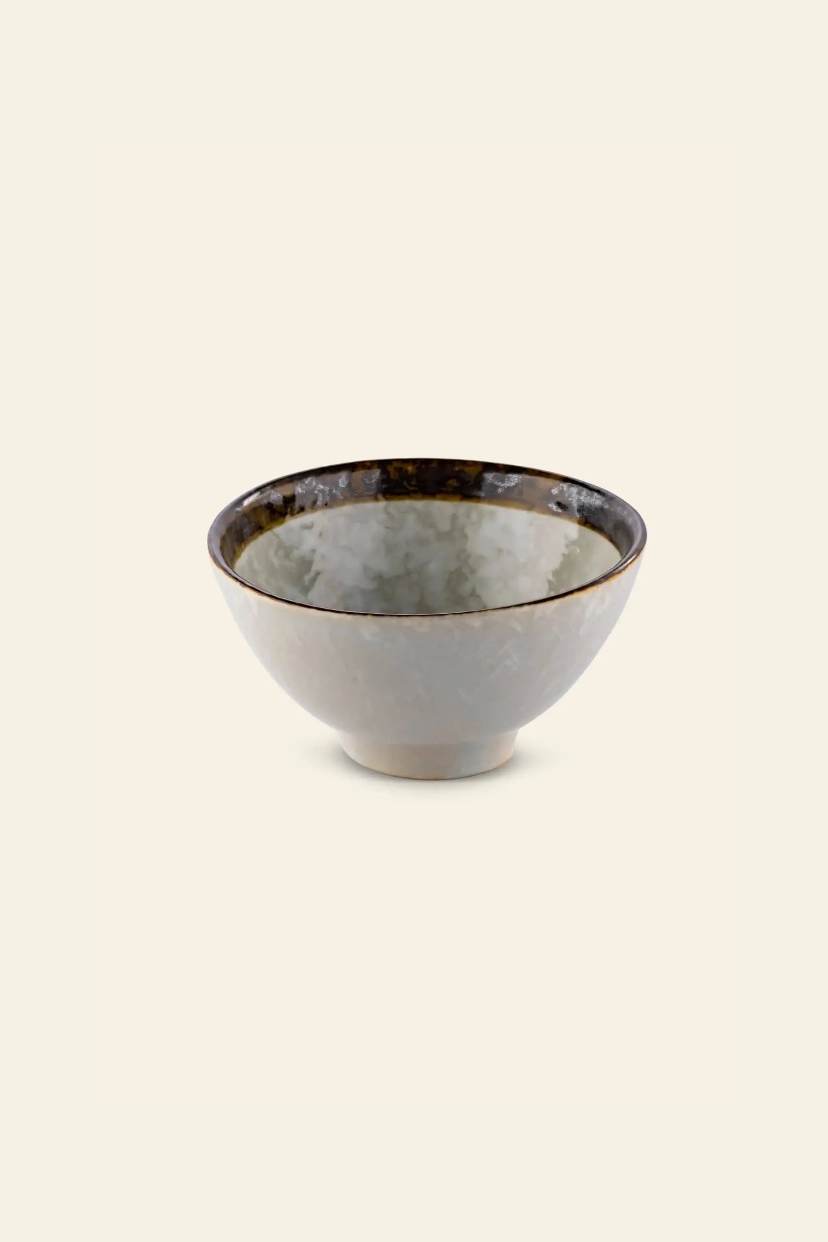The Kra Sanctuary Satay Everyday Rice Bowl by Kra Sanctuary features a glossy, marbled gray exterior with a dark brown rim, creating an earthy look thats beautifully showcased against a plain, light beige background.