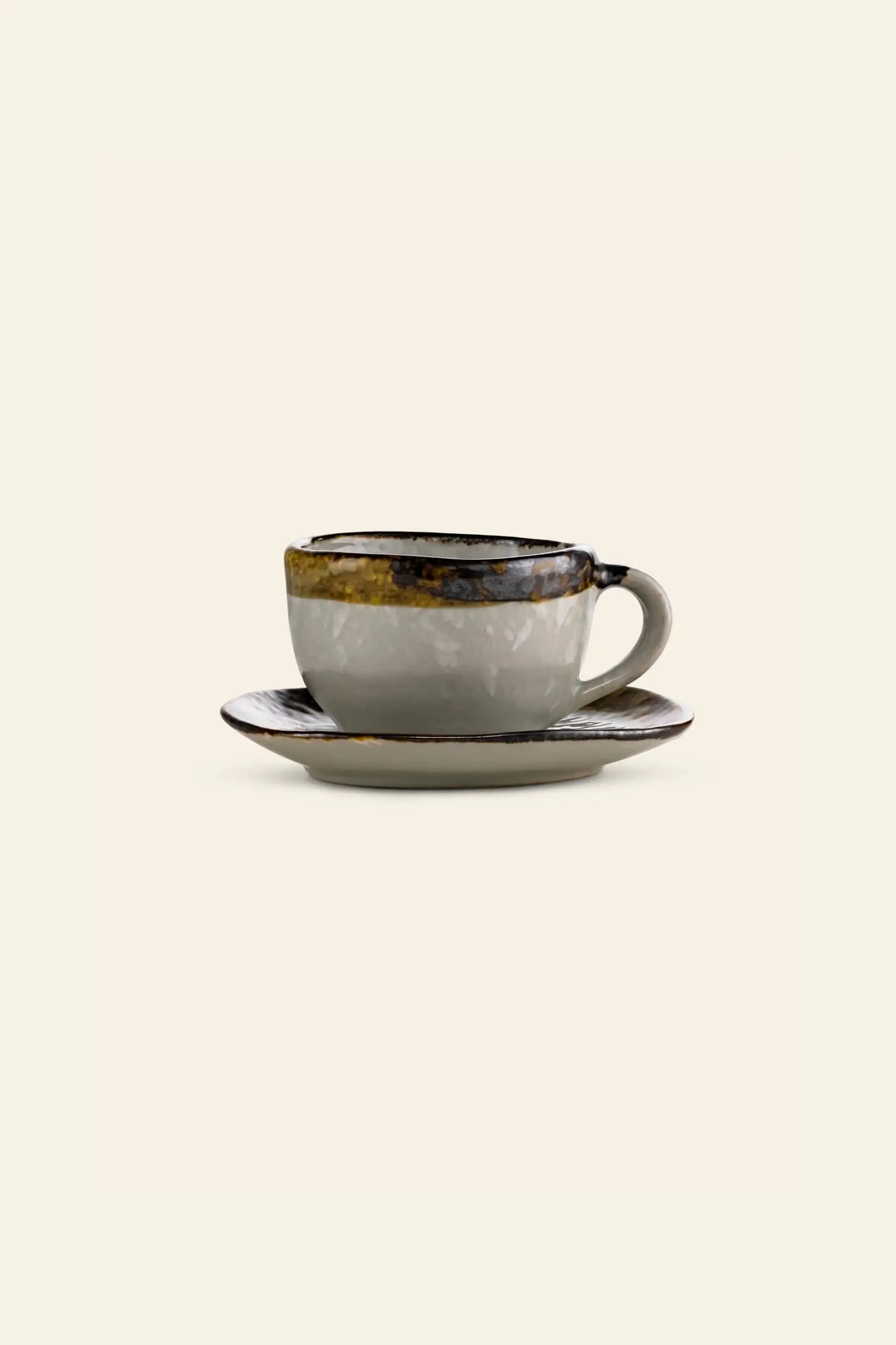The Kra Sanctuary Satay Free-Form Cup with handle and matching coaster by Kra Sanctuary features a glossy, earthy palette of brown, yellow, and gray with an iridescent border, shown against a plain beige background.