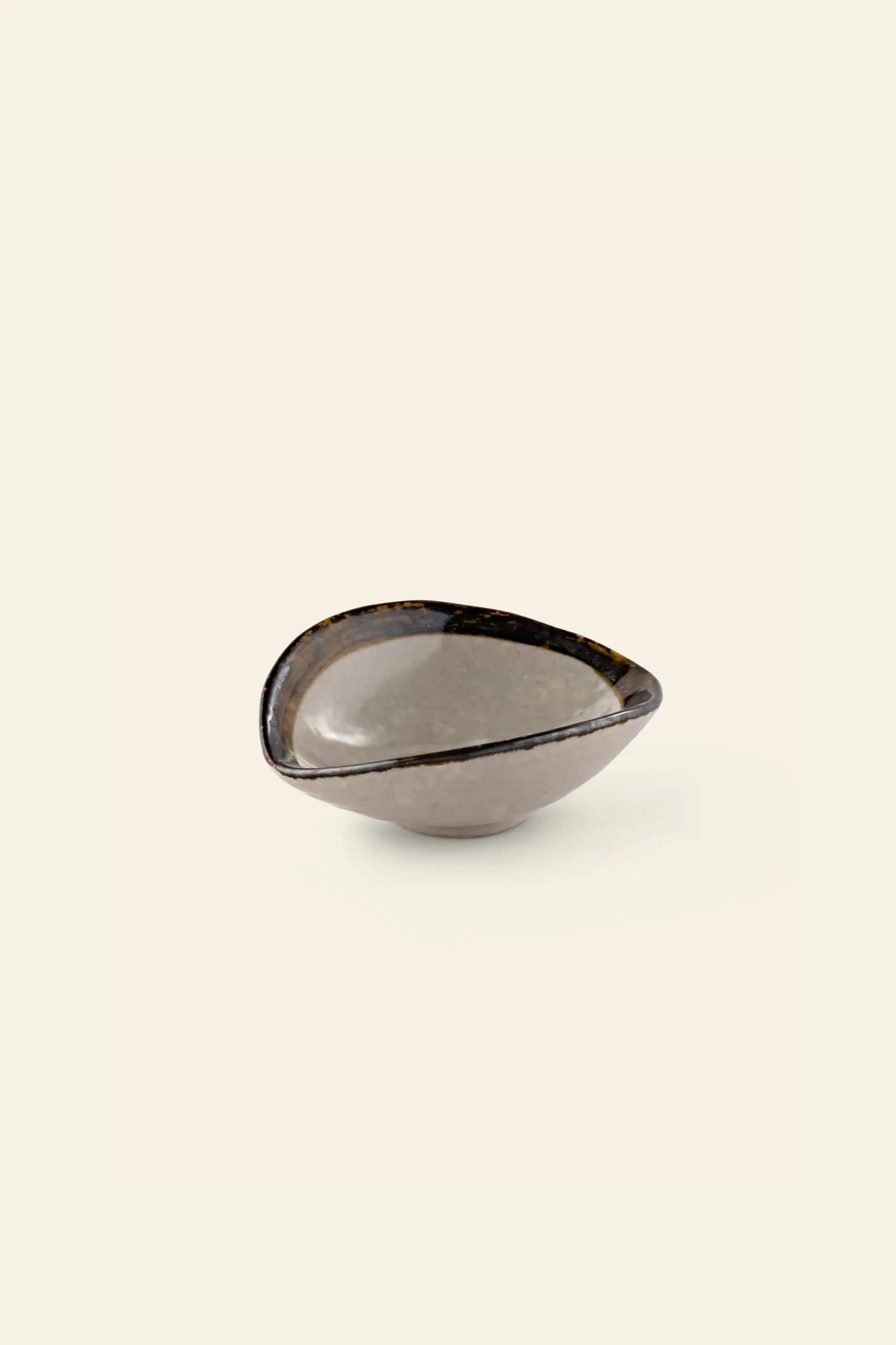 The Kra Sanctuary Satay Shell Dipping Dish by Kra Sanctuary is a small, asymmetrical ceramic bowl featuring a glossy gray and brown mottled finish with an iridescent border—an ideal addition to your earthy dinnerware collection.