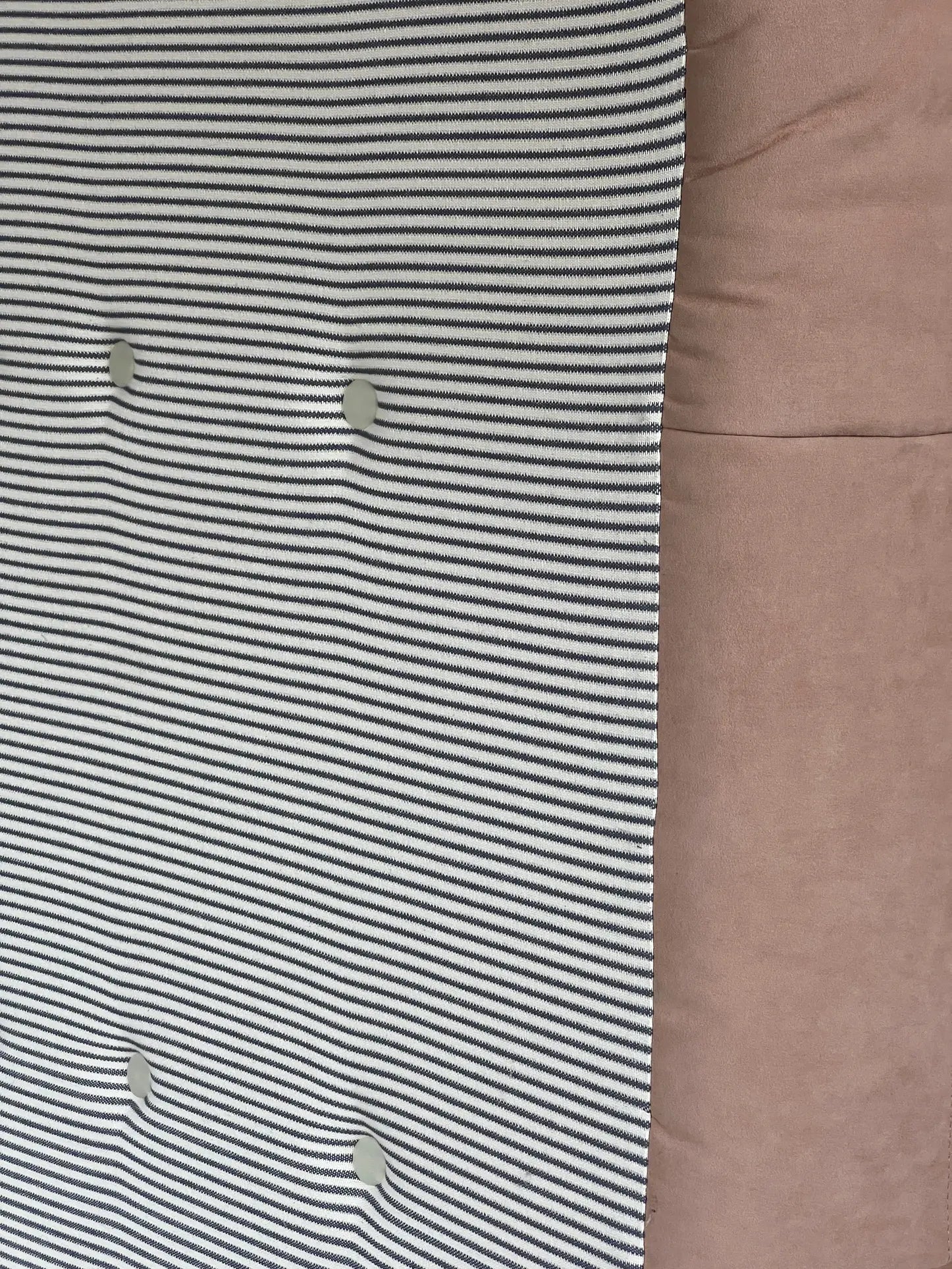 Close-up of the Ligne Roset Togo, 2 Seater by Ligne Roset, featuring horizontal black and white stripes with four round buttons on the left, next to smooth light brown fabric on the right, highlighting its mid-century modular design.