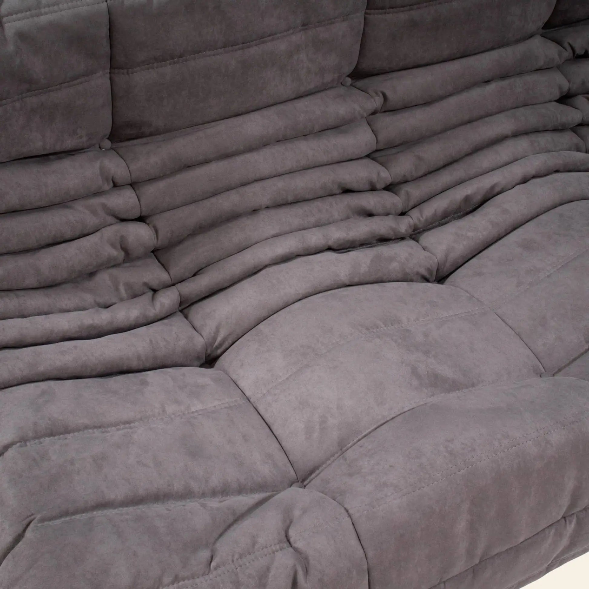 Close-up of the Ligne Roset Togo 3 Seater by Ligne Roset: a modern gray sofa with plush layered cushions, soft textured fabric, and a modular design that emphasizes contemporary comfort.