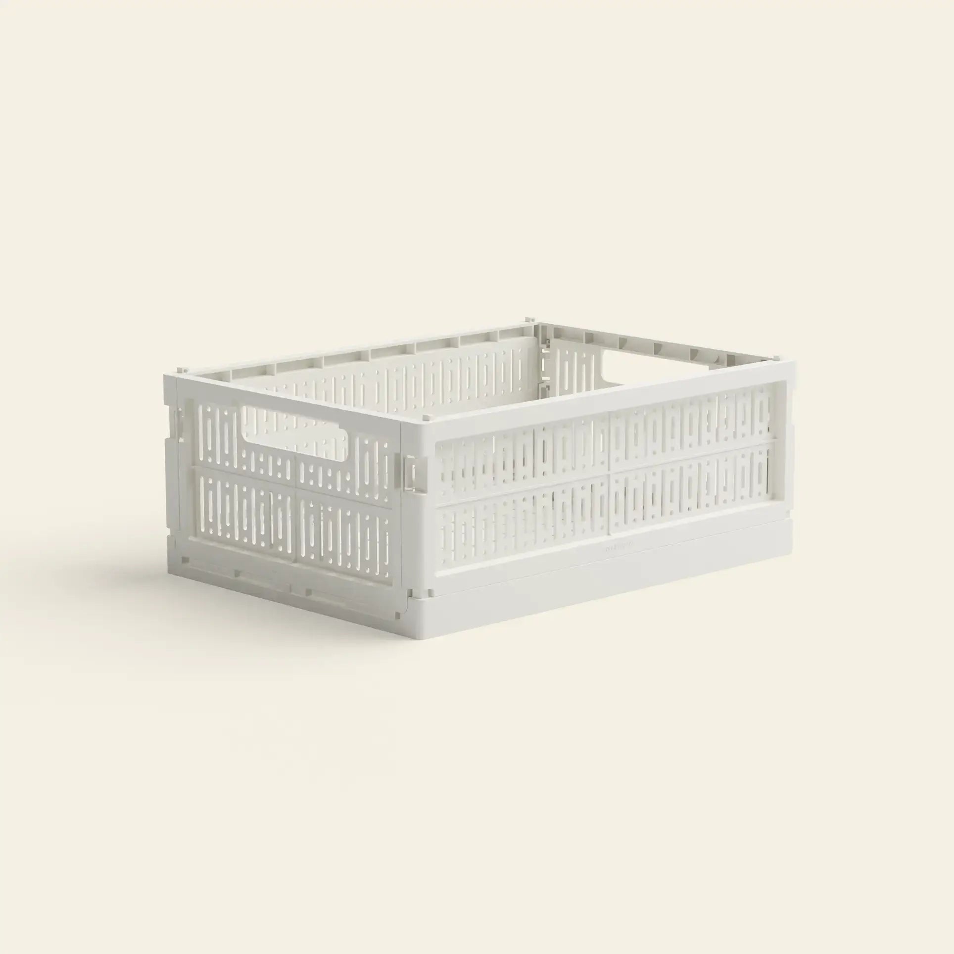 The Made Crate Midi by Made Crate is a white, rectangular, eco-friendly folding crate with open sides and handles at both ends, made from recycled plastic and displayed on a light beige background.