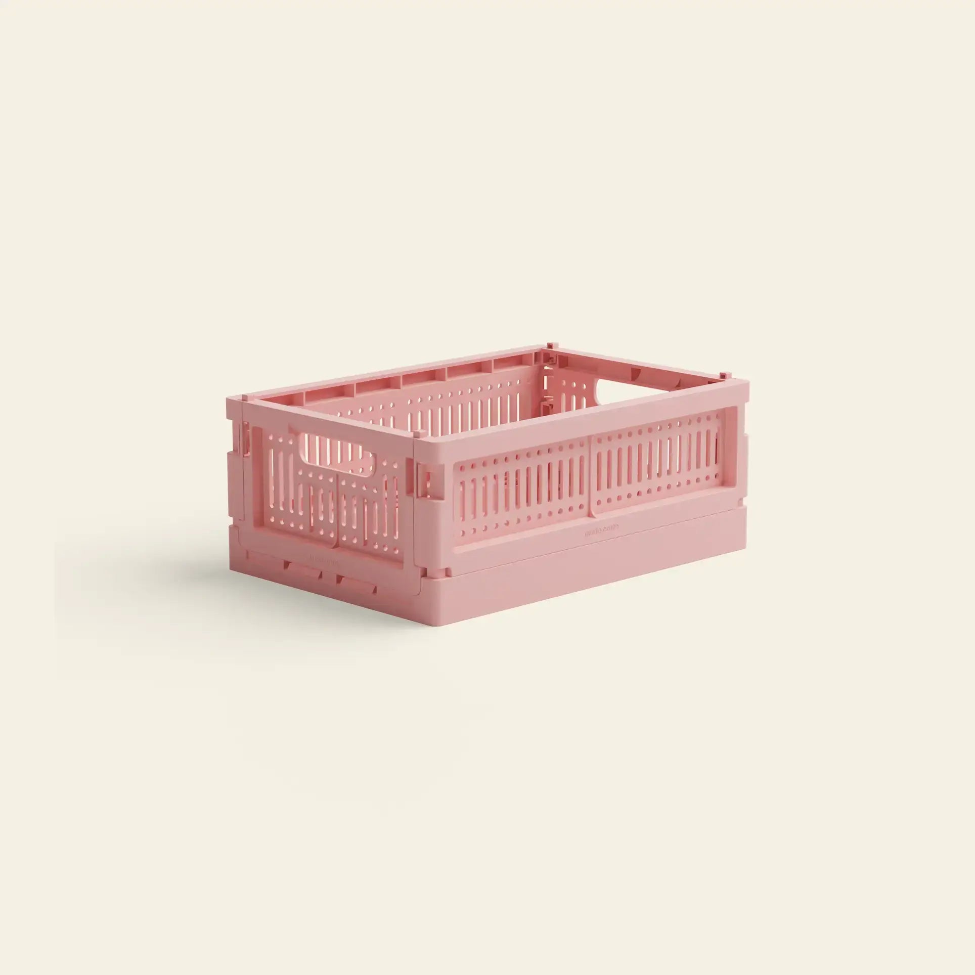 The Made Crate Mini by Made Crate is a light pink, rectangular recycled plastic storage crate with ventilation holes and open handles for easy stacking, shown on a plain light beige background.