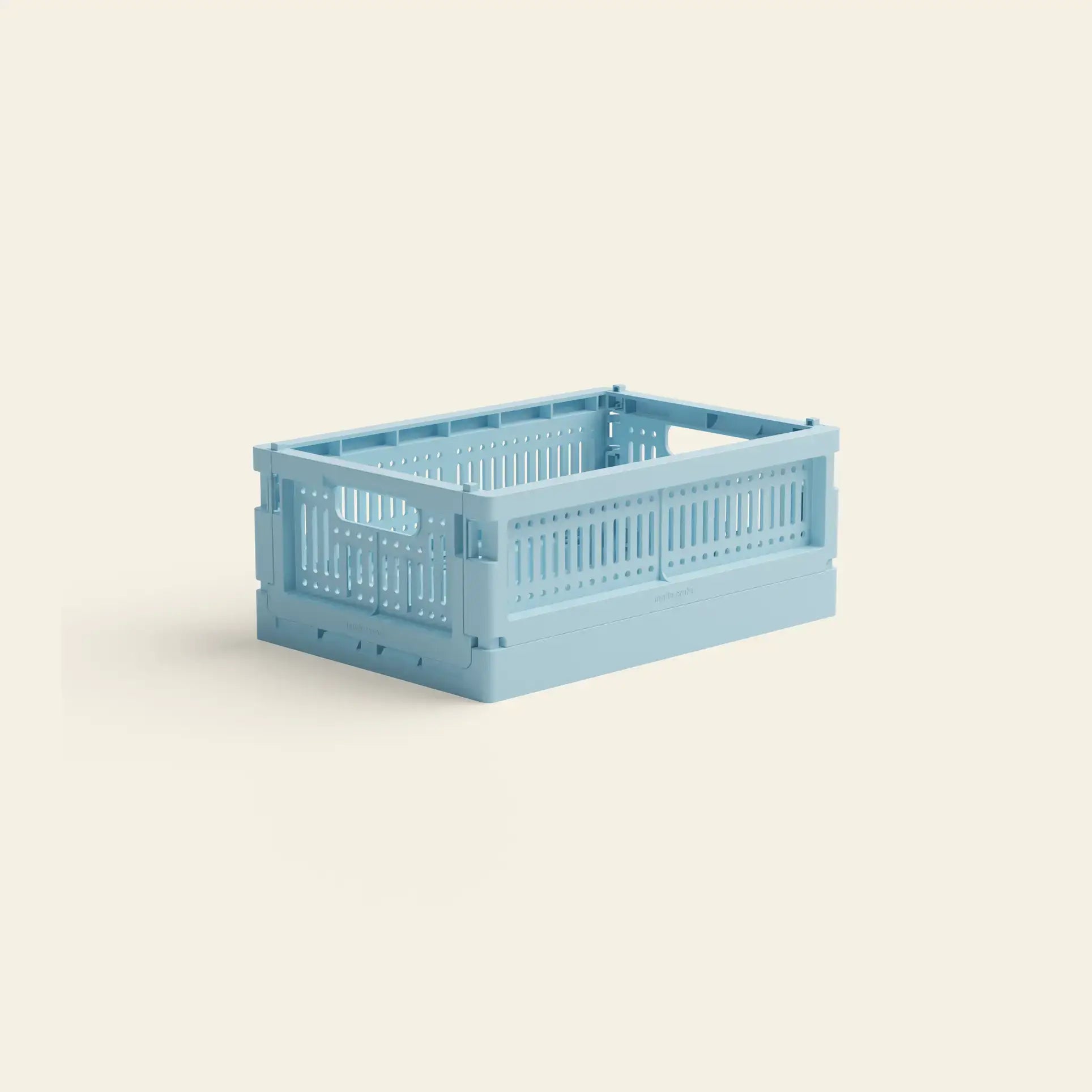 The Made Crate Mini by Made Crate is a light blue recycled plastic storage crate with slotted sides and handles for stacking, shown on a plain beige background.