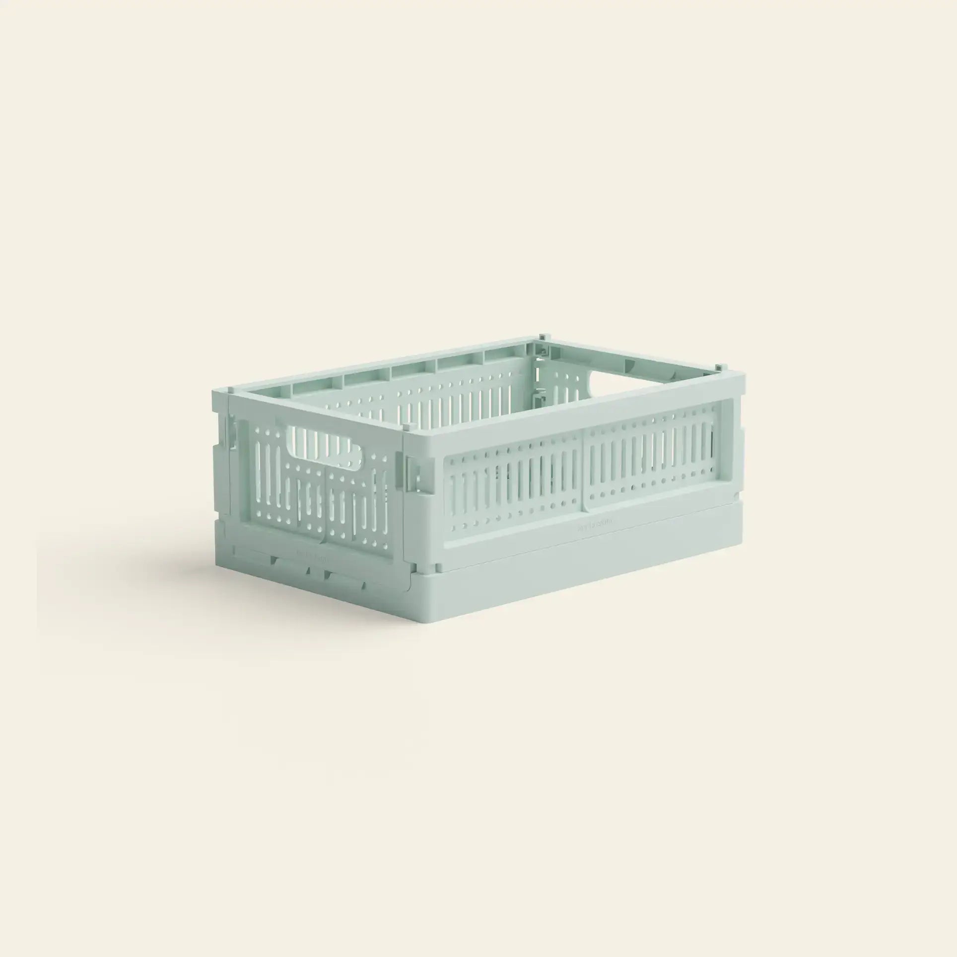 The Made Crate Mini by Made Crate is a light green, rectangular eco-friendly folding crate with ventilated sides and handles, crafted from recycled plastic, displayed on a plain light beige background.