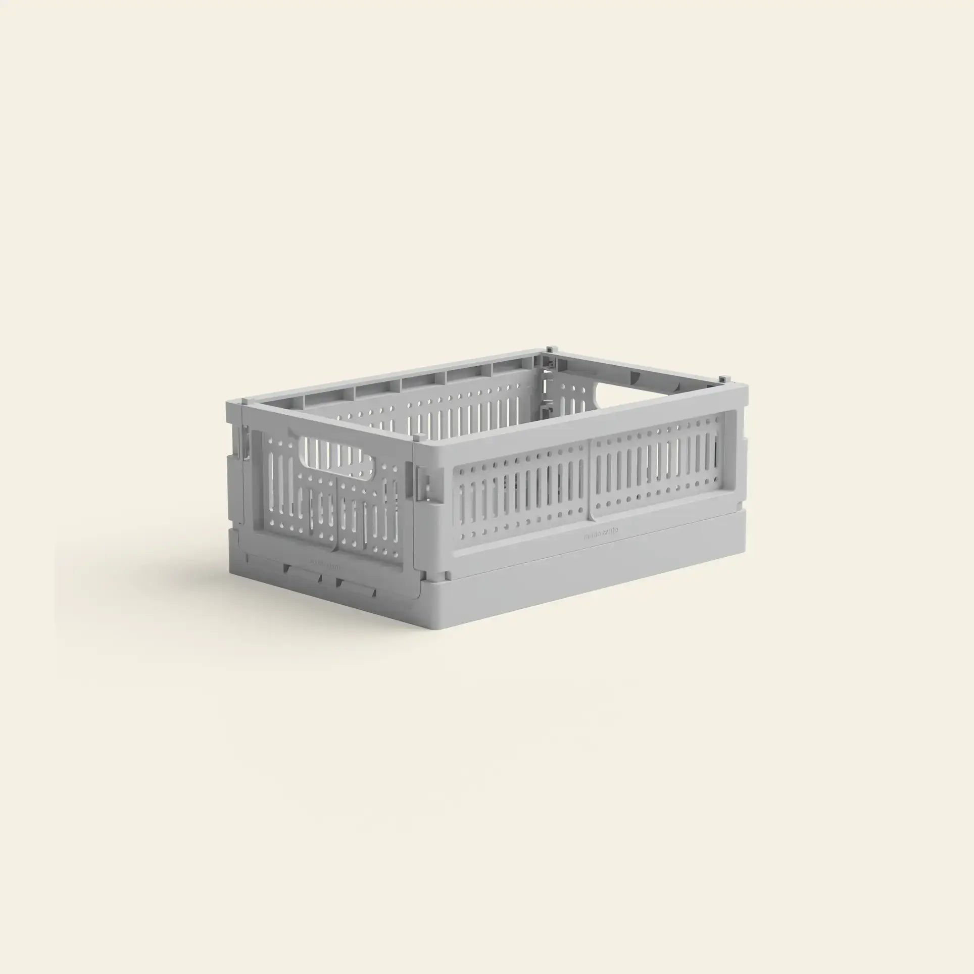 The Made Crate Mini by Made Crate is a light gray, rectangular crate with handles, crafted from recycled plastic for eco-friendly storage, shown on an off-white background.