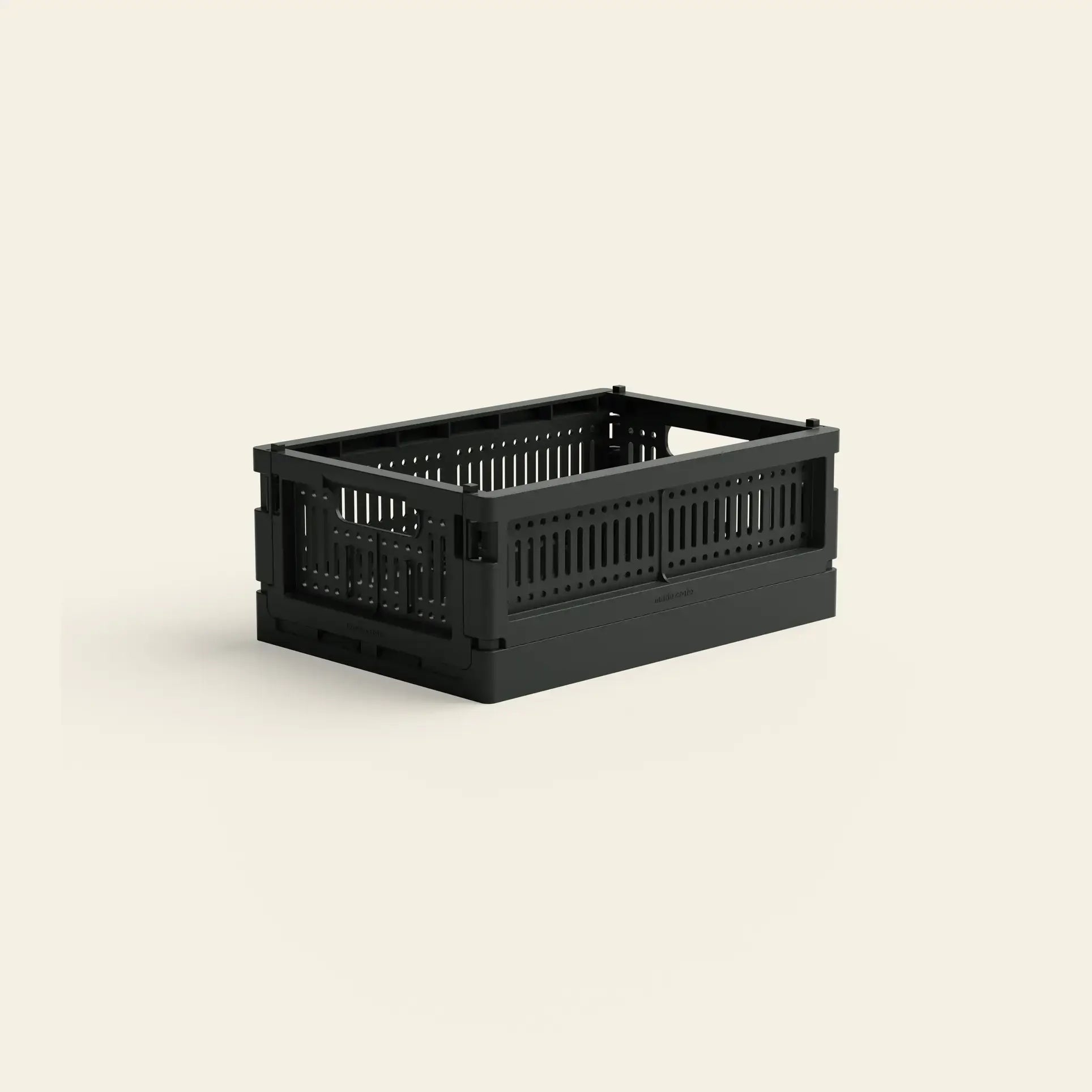 The Made Crate Mini by Made Crate is a black, rectangular storage crate made from recycled plastic with ventilated sides and an open top, shown on a light beige background. Experience eco-friendly stacking with this foldable crate.