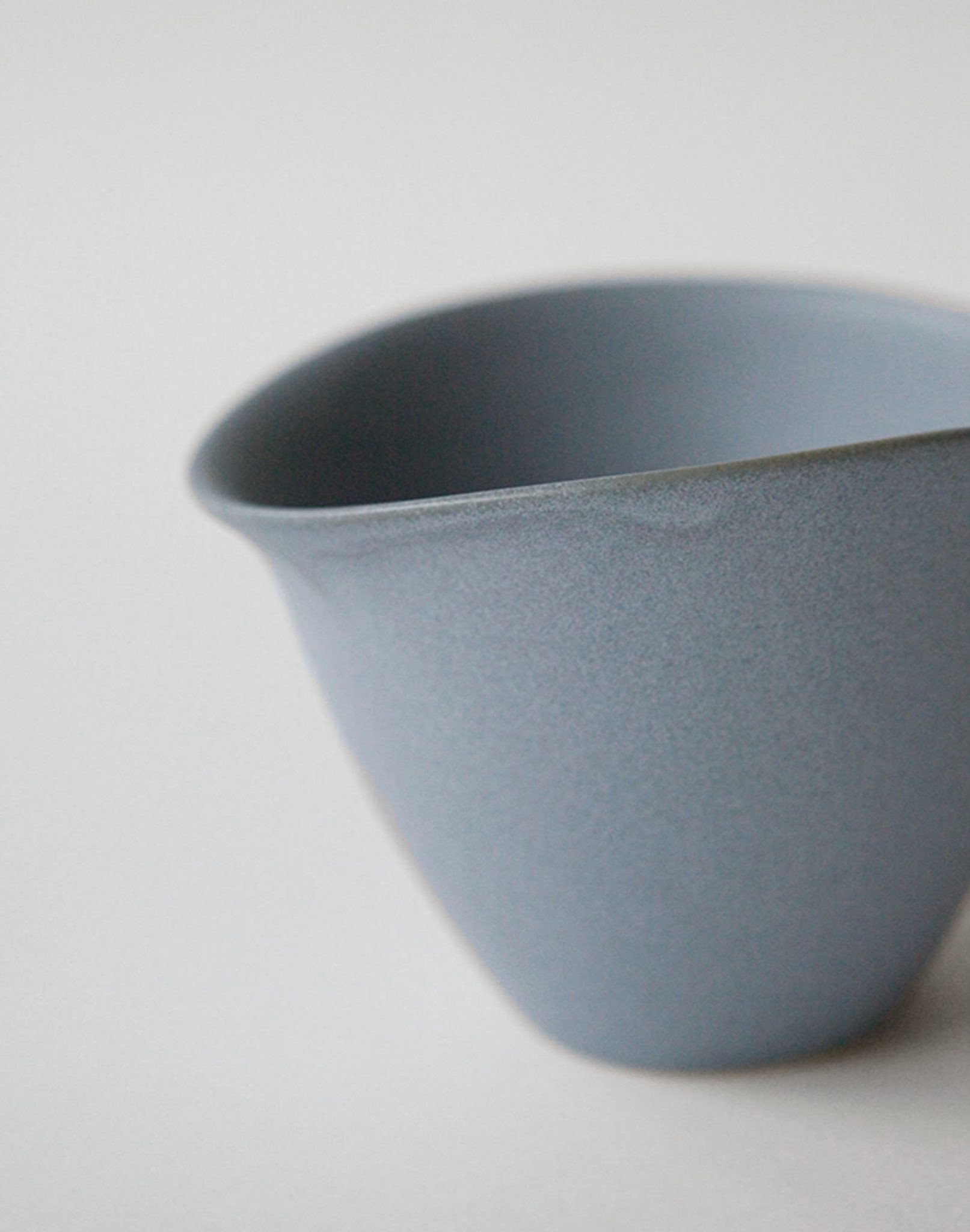 A close-up of the NR Ceramics HIN Tea Cup in matte light blue, featuring a smooth curved rim and ergonomic design, by NR Ceramics, set against a plain light background.