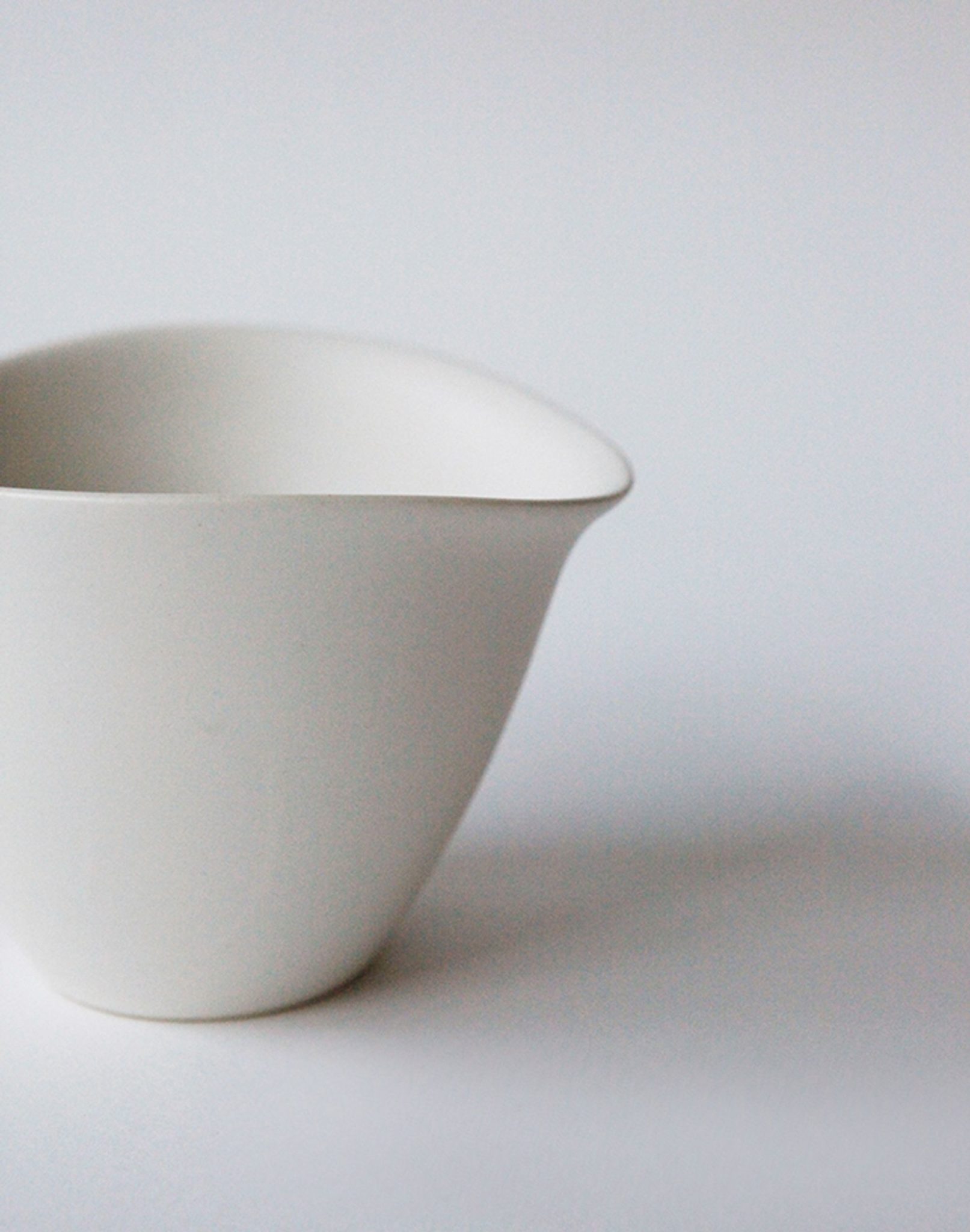 The NR Ceramics HIN Tea Cup, a plain white ceramic cup from NR Ceramics, sits on a light surface against a white background, creating a minimalistic and clean look.