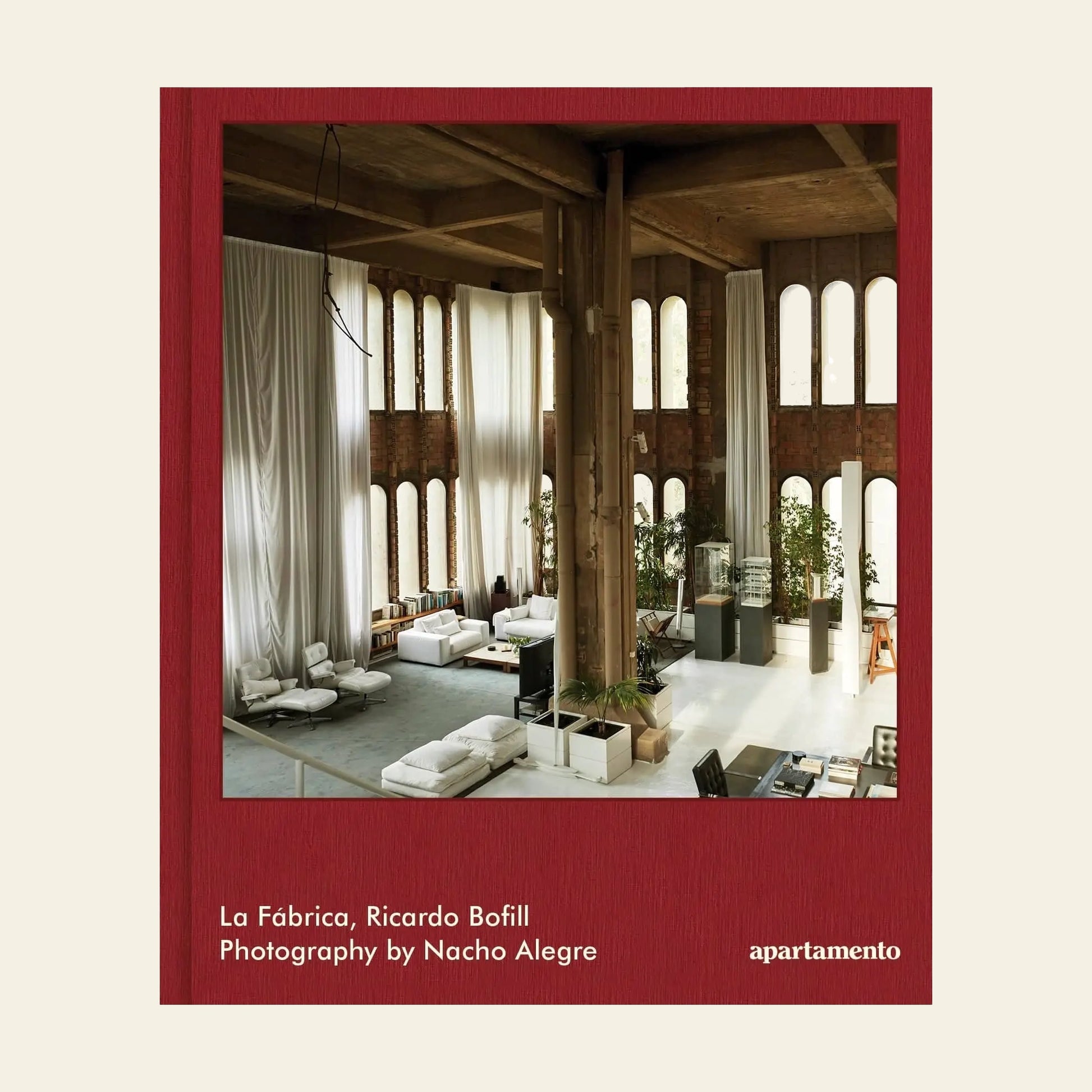 Apartamento La Fábrica by Apartamento features an industrial-inspired interior with tall columns, arched windows, white sofas, and lush greenery. Natural light enhances this modern, airy space inspired by Ricardo Bofill’s iconic design.