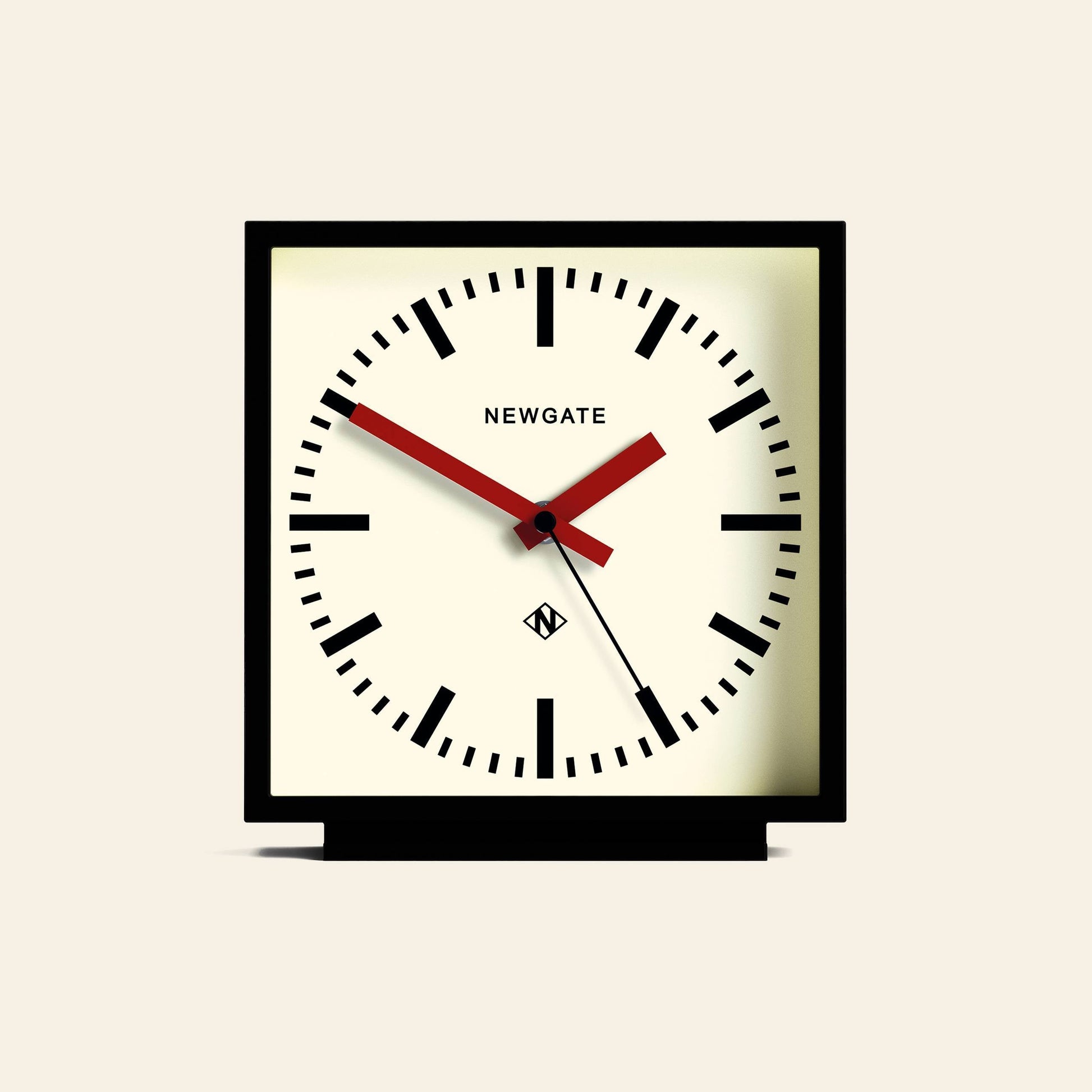 The Newgate Amp Mantel Clock features a square black frame, white face, bold black hour markers, black hands, and a red second hand. NEWGATE is printed near the center for a modern touch on classic station clock design.