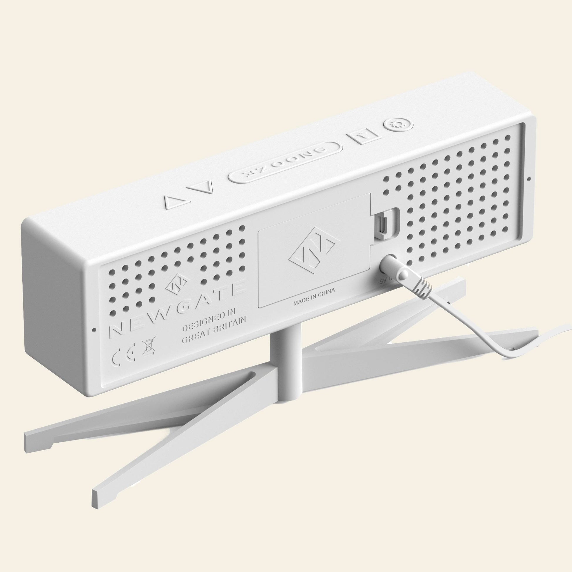 A white rectangular Newgate Supergenius LCD Alarm Clock with ventilation holes, a stand, and a USB power cable at the back. The device shows brand labels, certification marks, “Made in China,” plus an LCD alarm and temperature display.