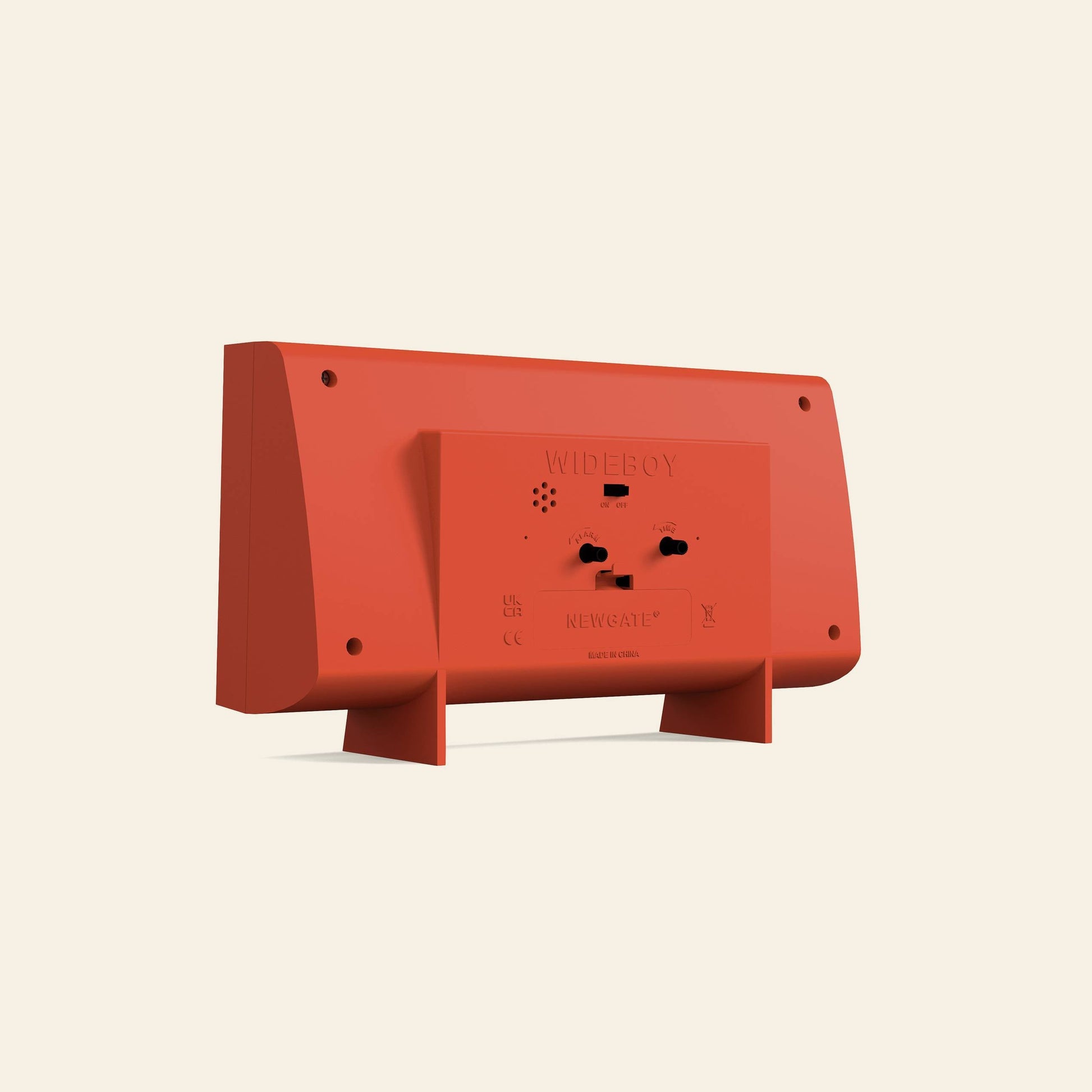 The Newgate Wideboy Alarm Clock by Newgate is shown from the back, displaying its rectangular red minimalist design with control buttons, vents, and a stand against a plain beige background.
