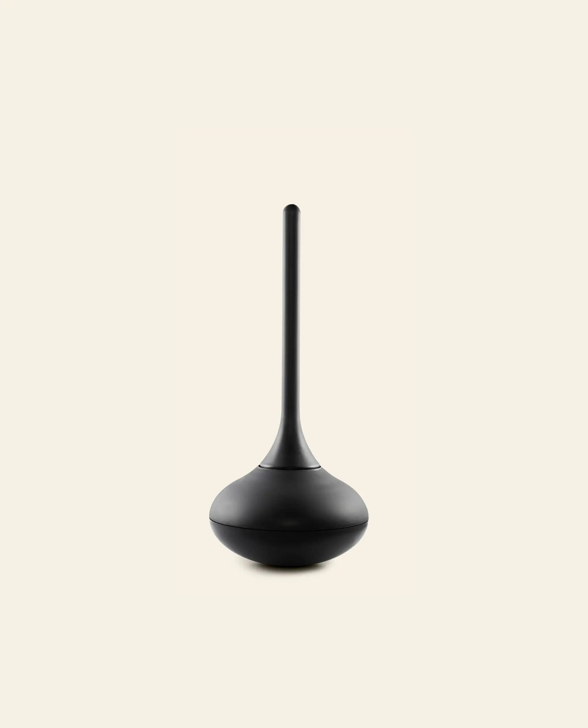 The Normann Copenhagen Ballo Toilet Brush, featuring a sleek black design with a long handle and rounded base, adds modern style to bathroom cleaning. Shown against a light beige background.