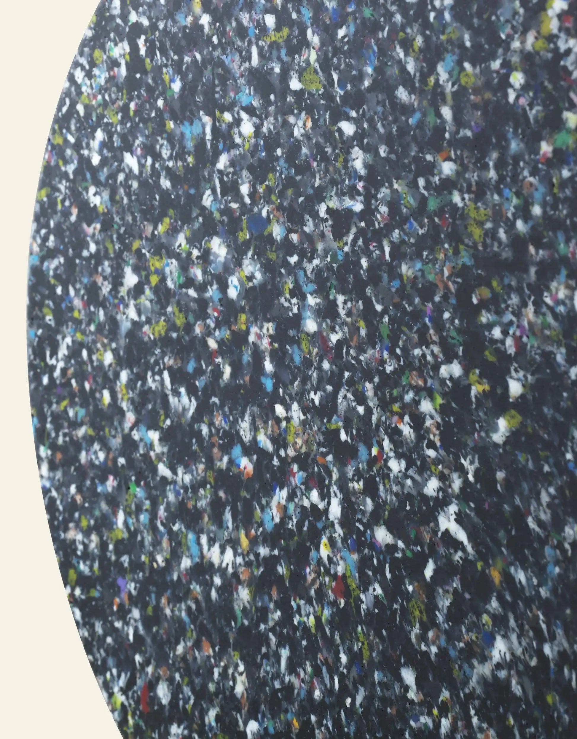 Close-up of the Normann Copenhagen Bit Stool, highlighting its dark, speckled surface with multicolored flecks against a plain background—a showcase of Normann Copenhagen’s multifunctional and versatile seating design.