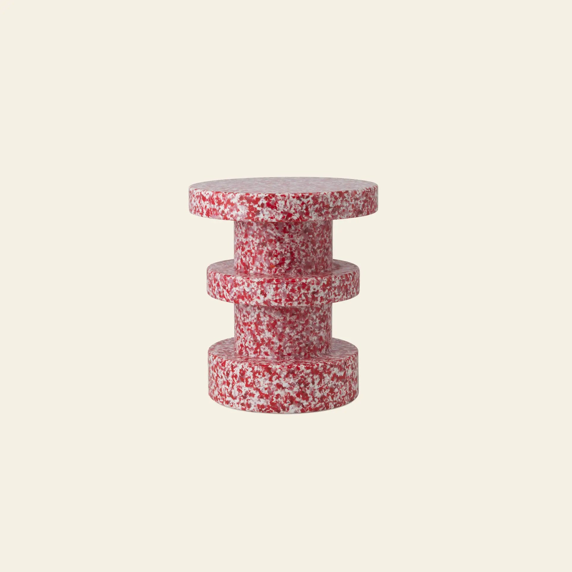 The Normann Copenhagen Bit Stool Stack features a small, modern cylindrical design with a red-and-white speckled texture, serving as both a side table and versatile seat against a plain light beige background.