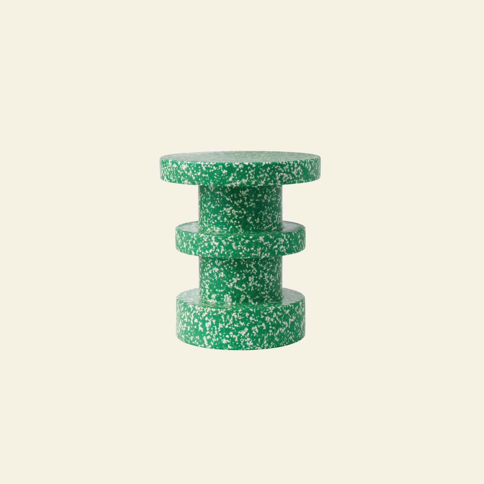 The Normann Copenhagen Bit Stool Stack by Normann Copenhagen is a compact, round green-and-white terrazzo side table with three stacked cylindrical sections, shown on a light beige background and emphasizing multifunctional design.