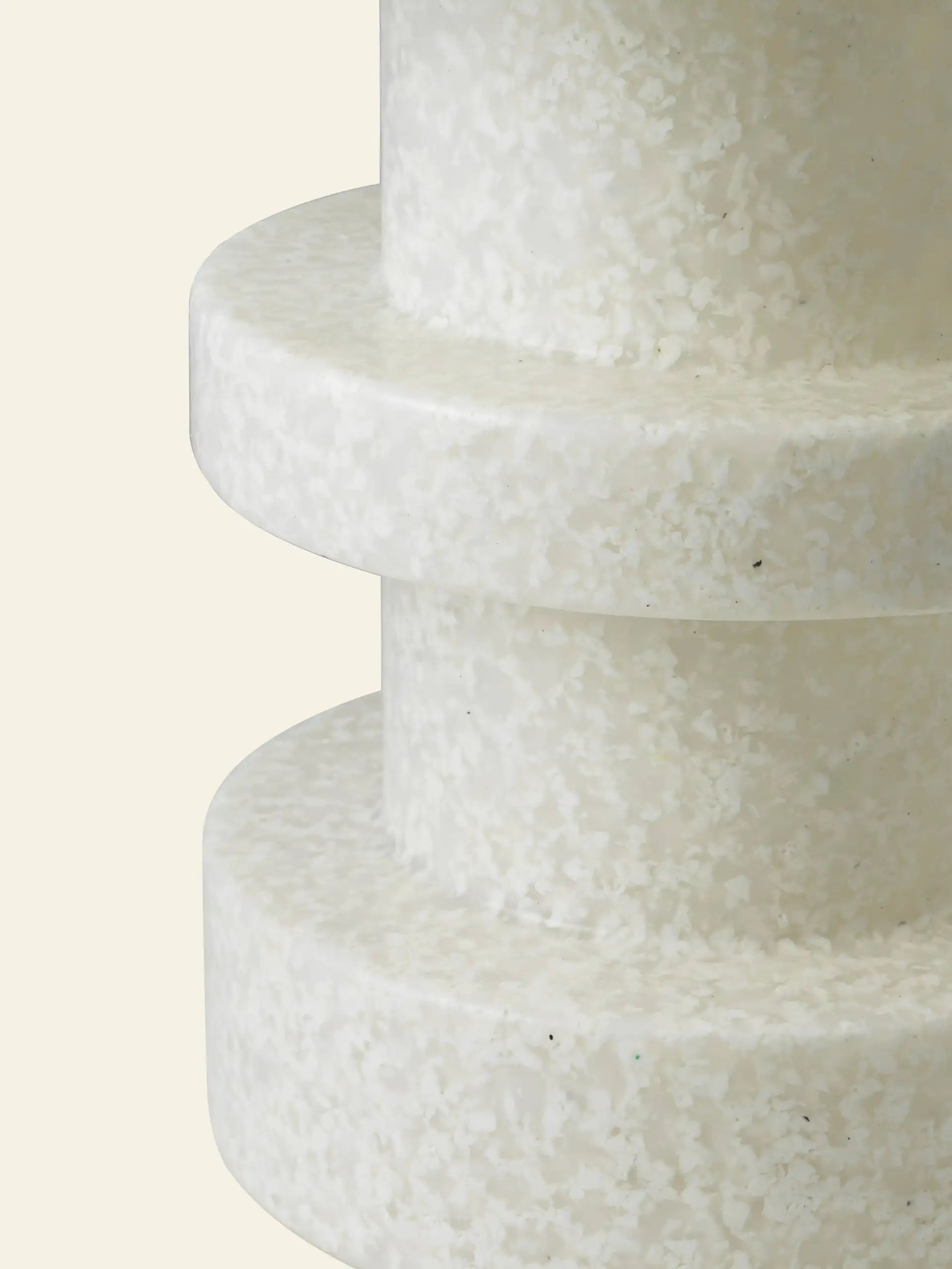 Close-up of the Normann Copenhagen Bit Stool Stack by Normann Copenhagen, featuring two stacked, circular white layers with a textured, speckled surface, set against a plain beige background for versatile seating options.
