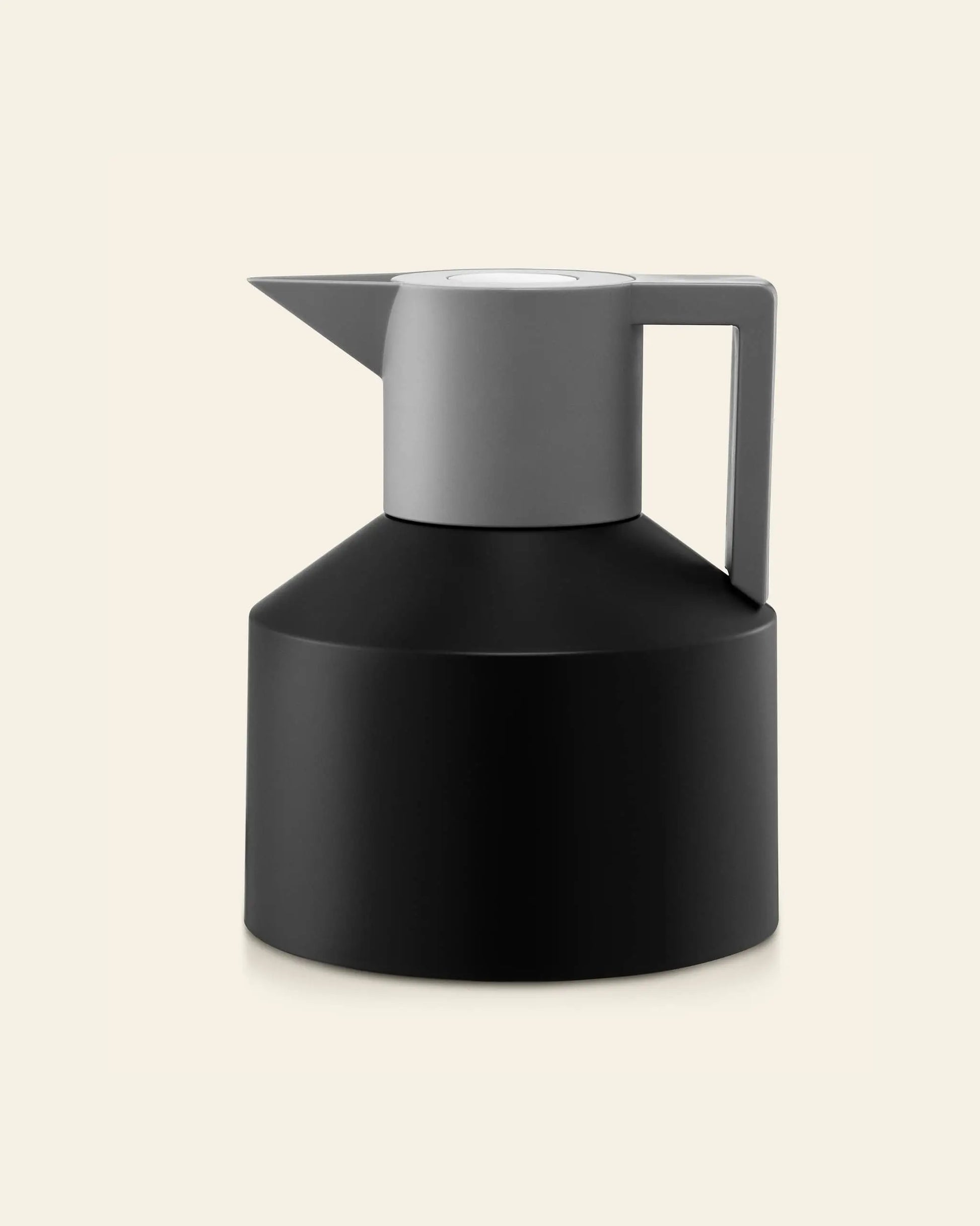 The Normann Copenhagen Geo Vacuum Jug by Normann Copenhagen features a modern geometric design in matte black and gray, with a vacuum-insulated body, sharp-angled spout, and sturdy handle against a plain light background.
